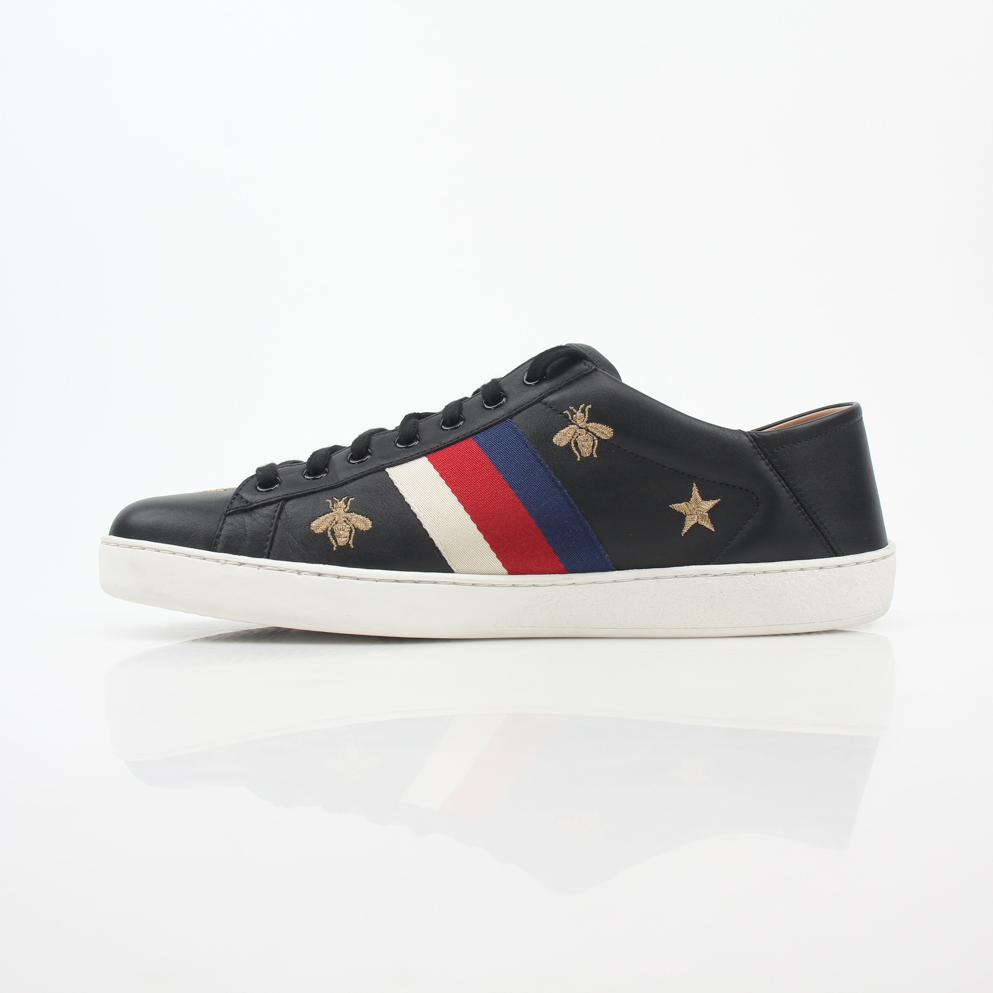 Gucci black embroidered Ace Web low-top sneakers with white soles and signature design, displayed on a plain background.