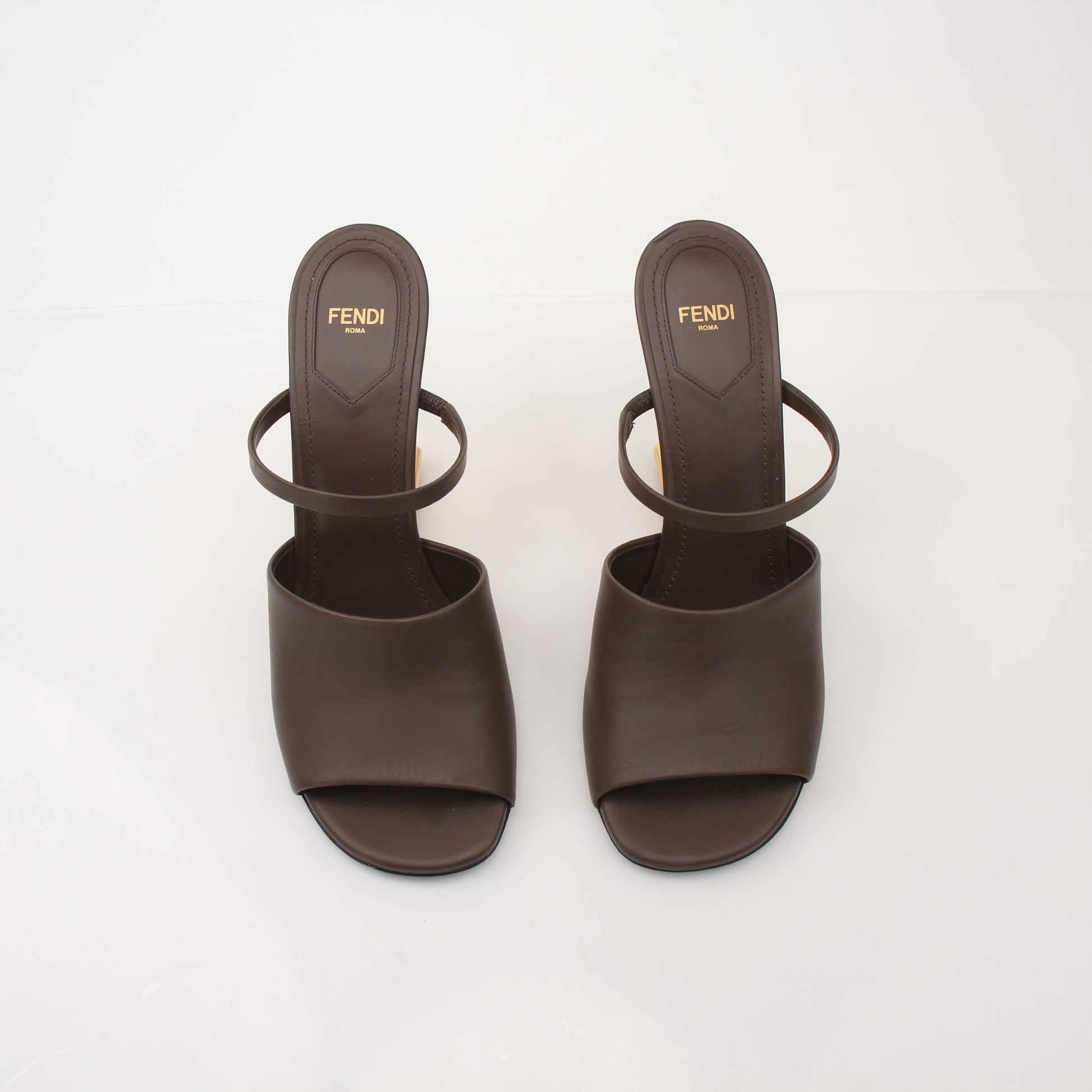 Fendi First sculpted heel sandals with gold-tone detailing and sleek straps, displayed on a neutral background.