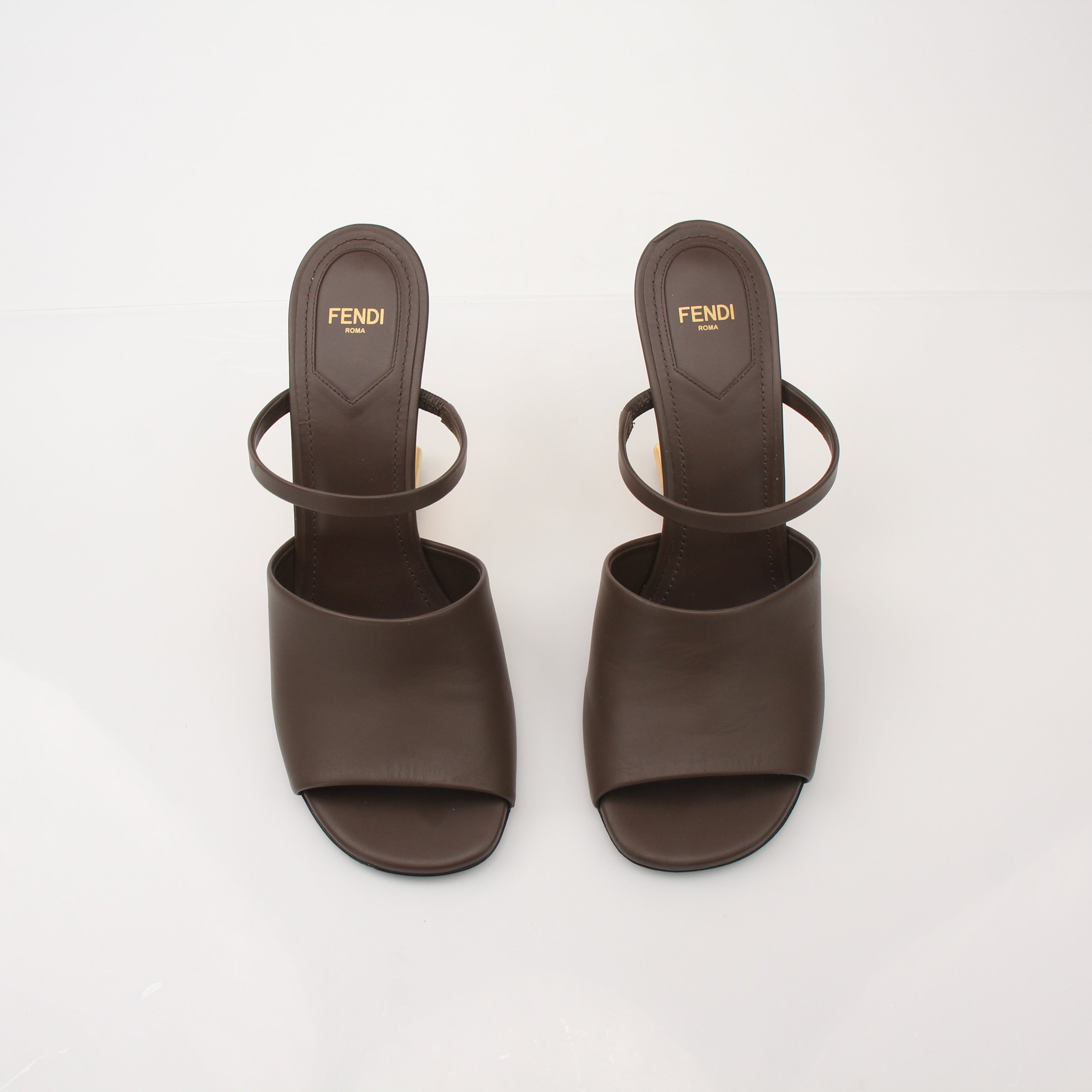 Fendi First sculpted heel sandals with gold-tone detailing and sleek straps, displayed on a neutral background.