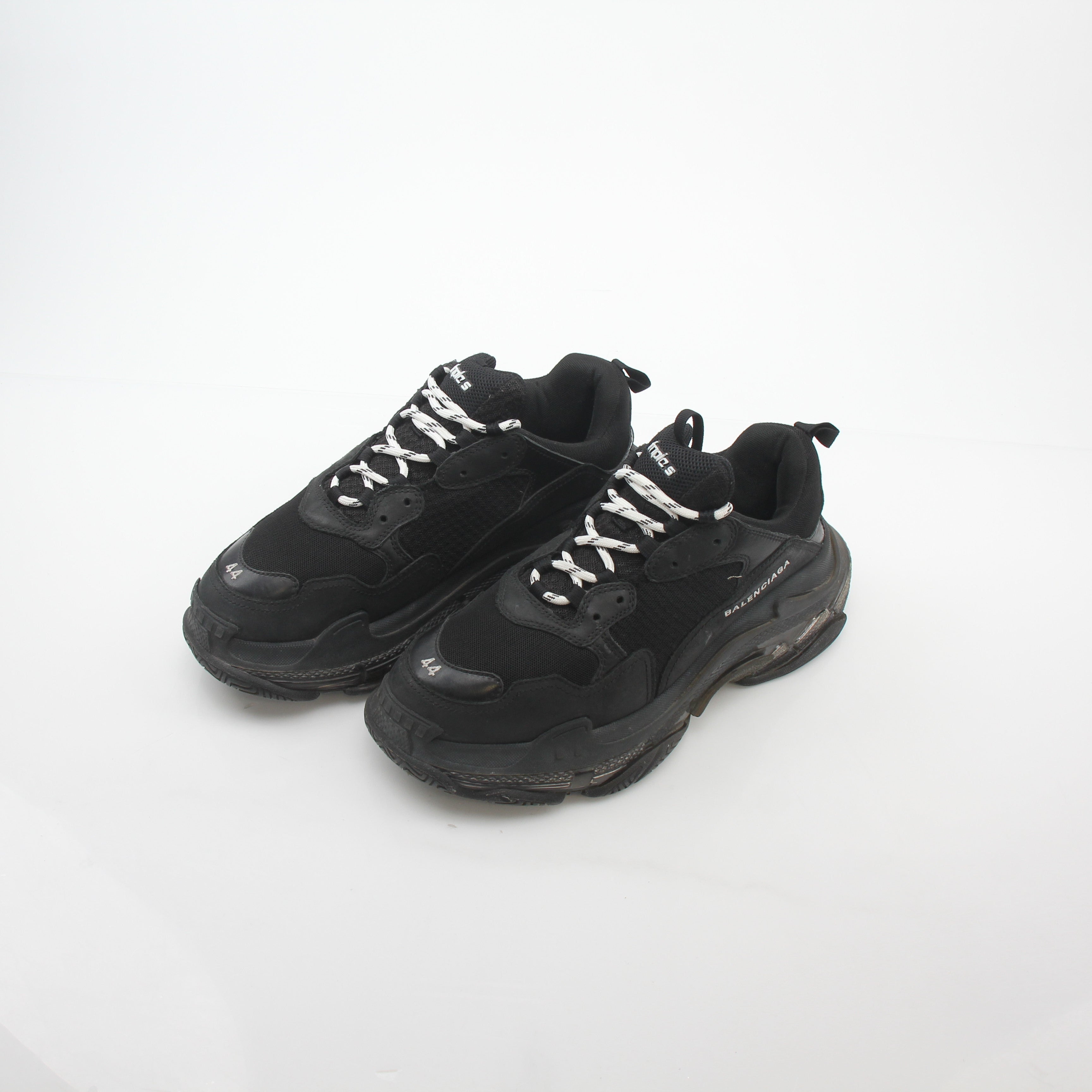 Black Balenciaga Triple S sneakers with clear soles, featuring chunky design and black laces, on a plain background.