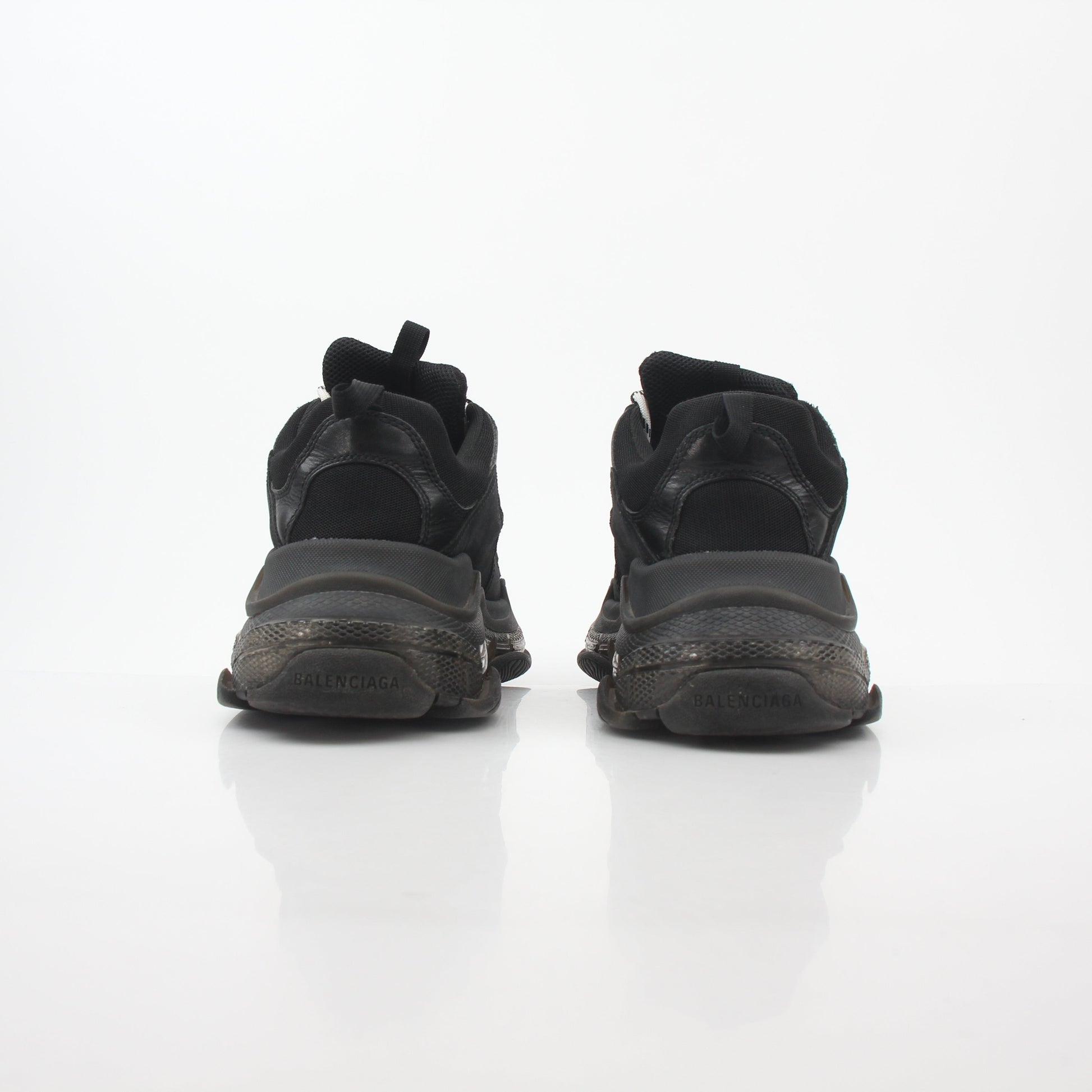 Black Balenciaga Triple S sneakers with clear soles, featuring a chunky design and branded details, displayed on a white background.