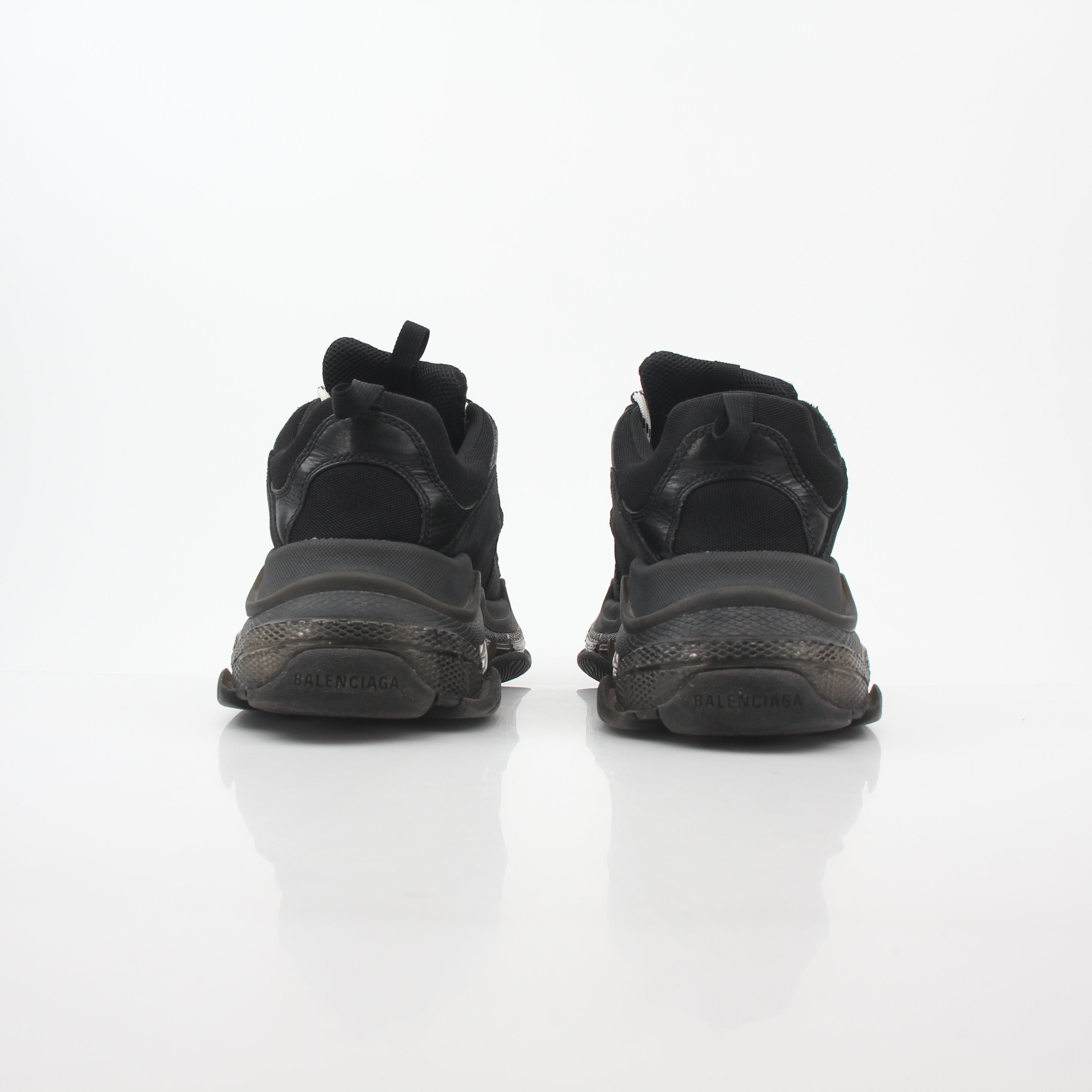Black Balenciaga Triple S sneakers with clear soles, featuring a chunky design and branded details, displayed on a white background.