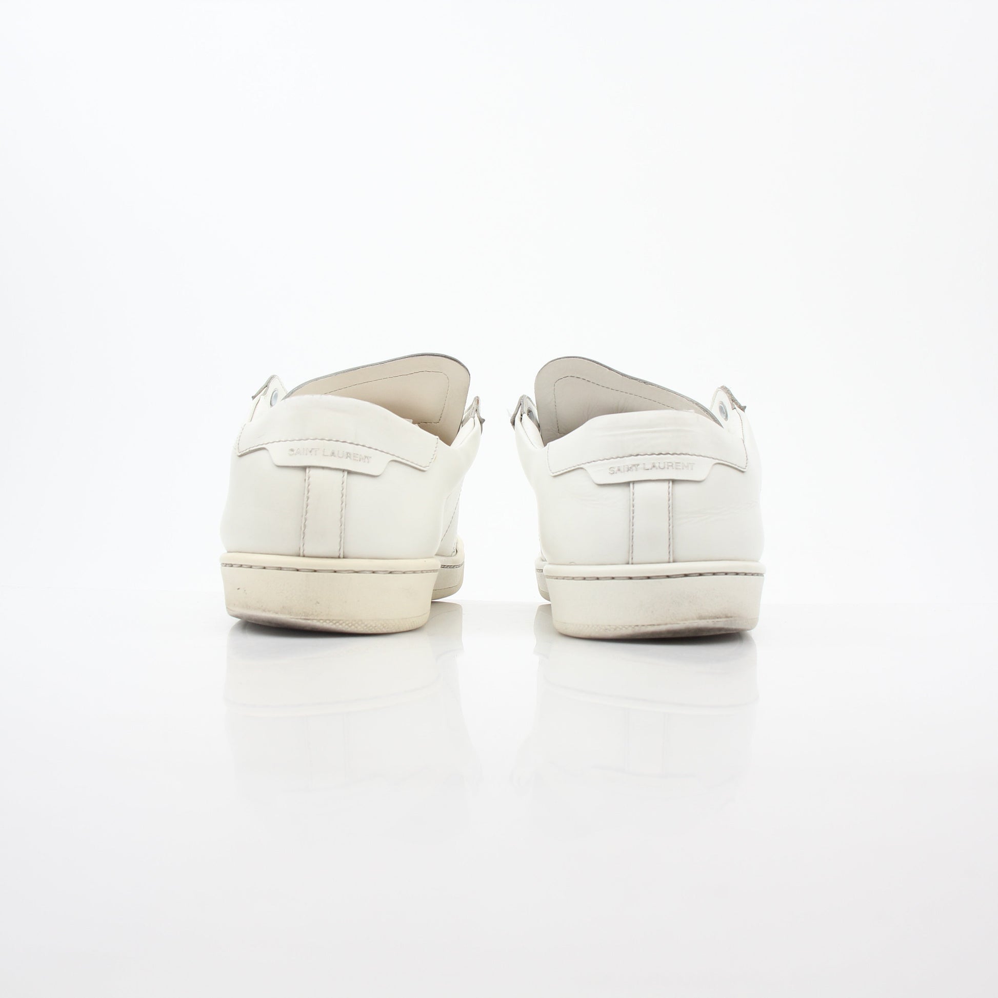 White Saint Laurent SL/06 Court Classic Sneakers worn on feet, showcasing sleek design and casual style.