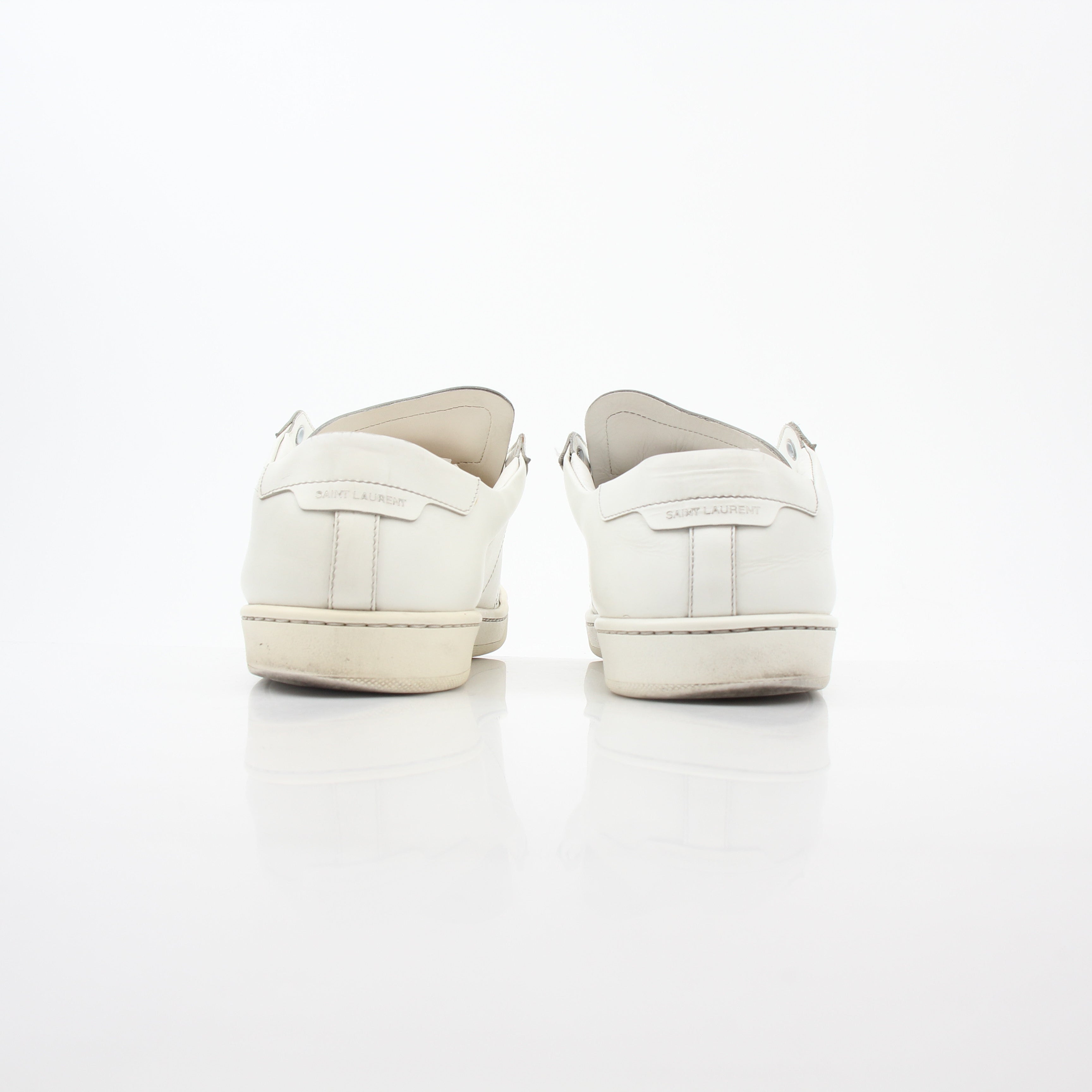 White Saint Laurent SL/06 Court Classic Sneakers worn on feet, showcasing sleek design and casual style.