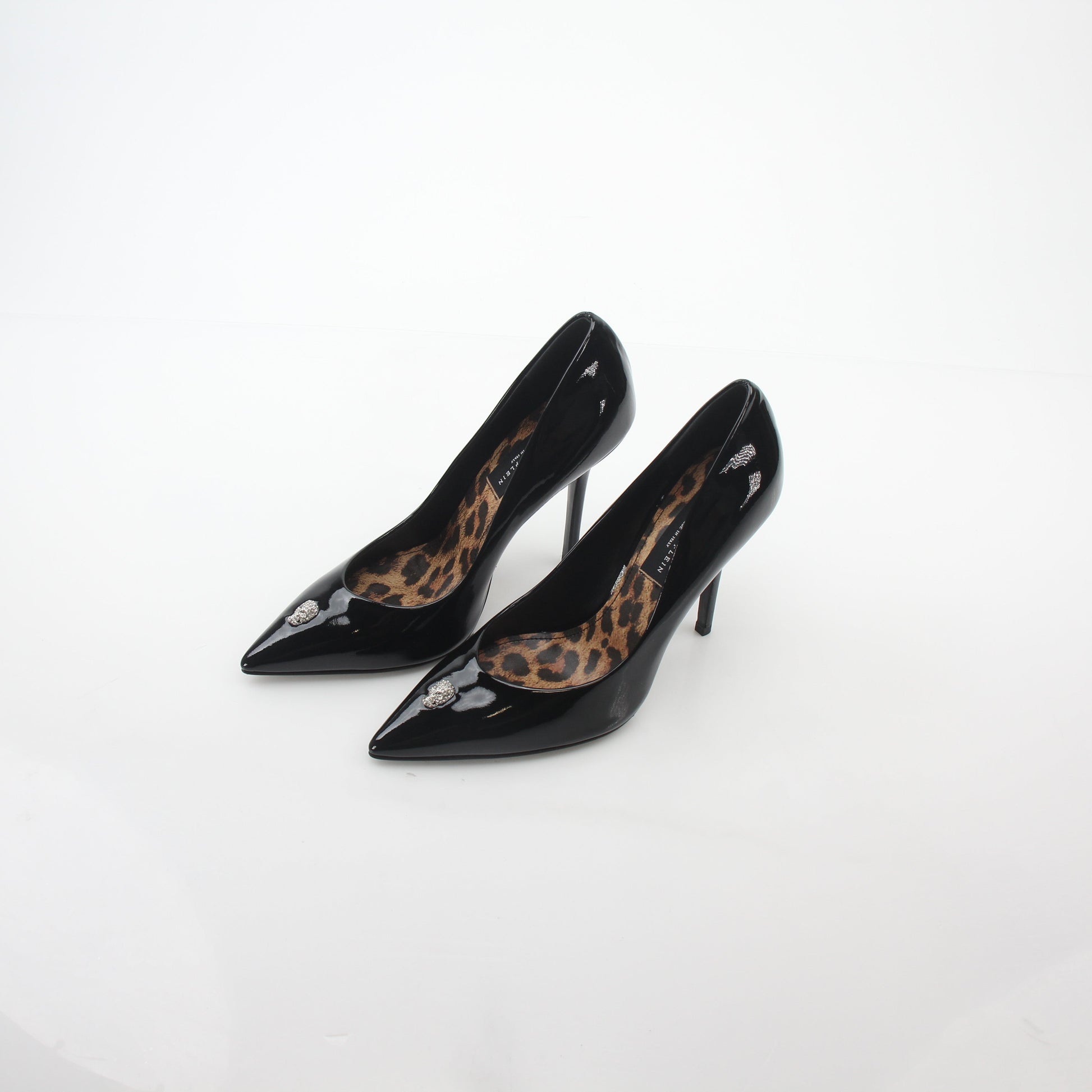 Black patent leather Philipp Plein crystal skull décolleté heels with pointed toes and decorative skull embellishments.