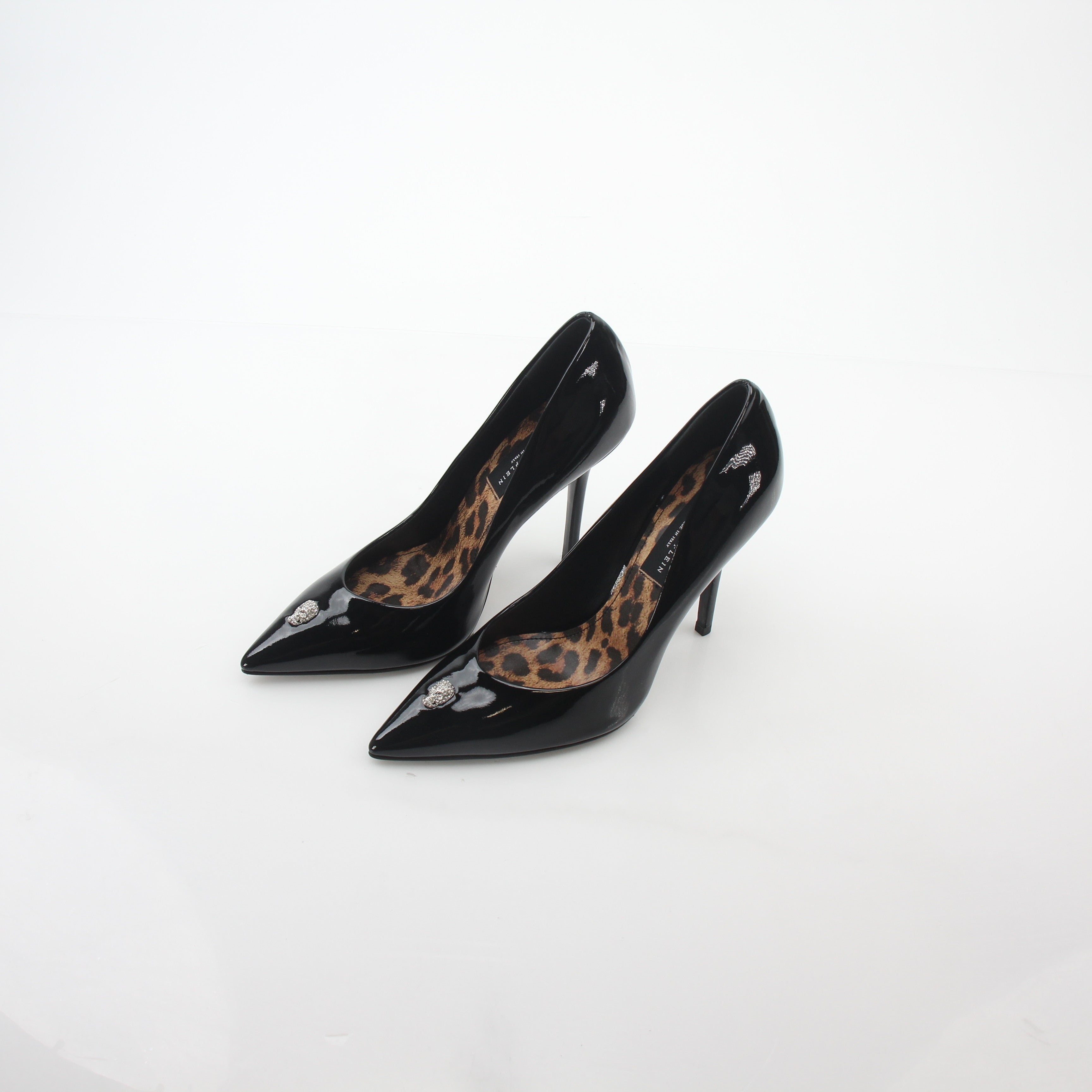 Black patent leather Philipp Plein crystal skull décolleté heels with pointed toes and decorative skull embellishments.