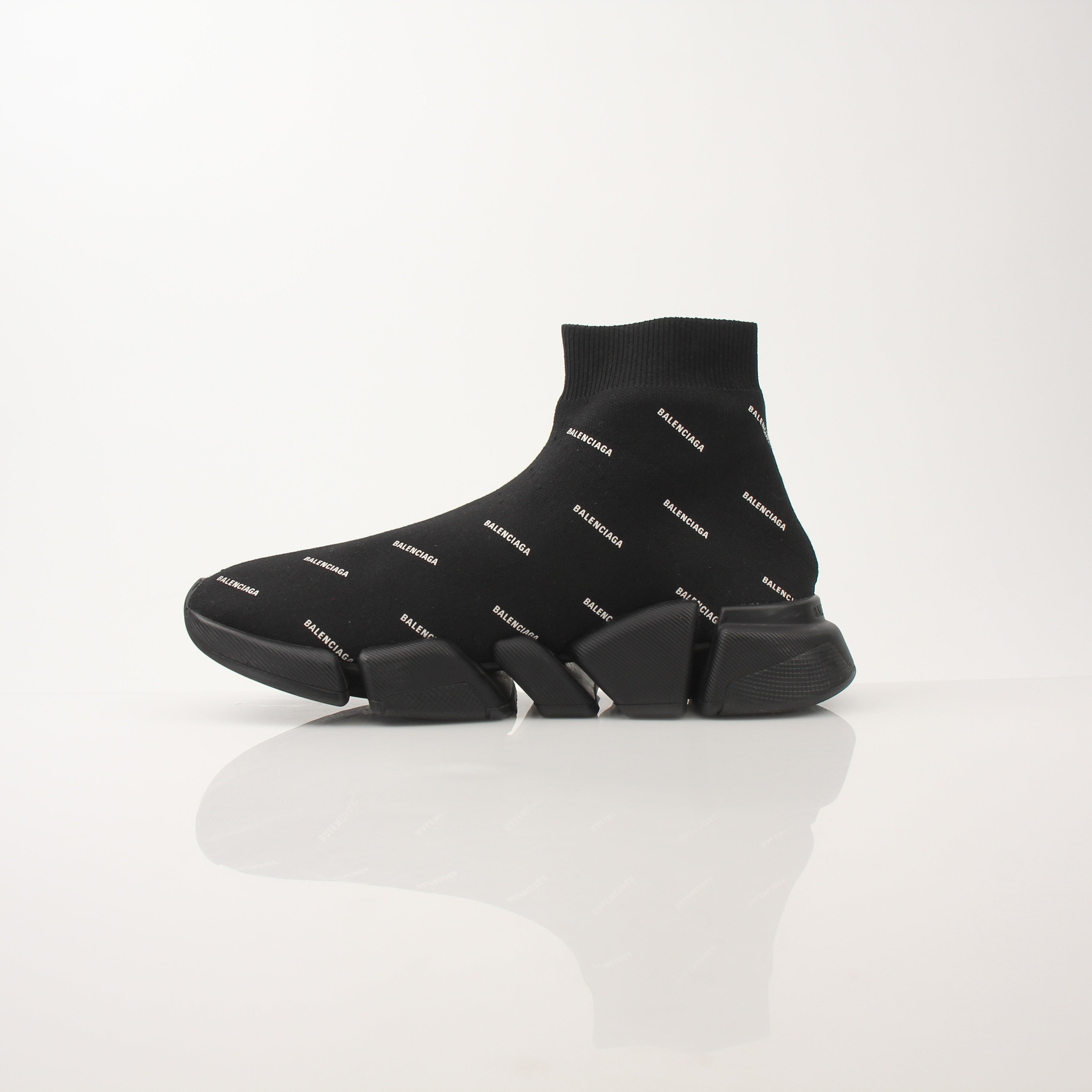 Gold & Beyond Balenciaga Women’s All Over Logo Speed 2.0 sneakers showing white shoes with bold logo print on the sides.