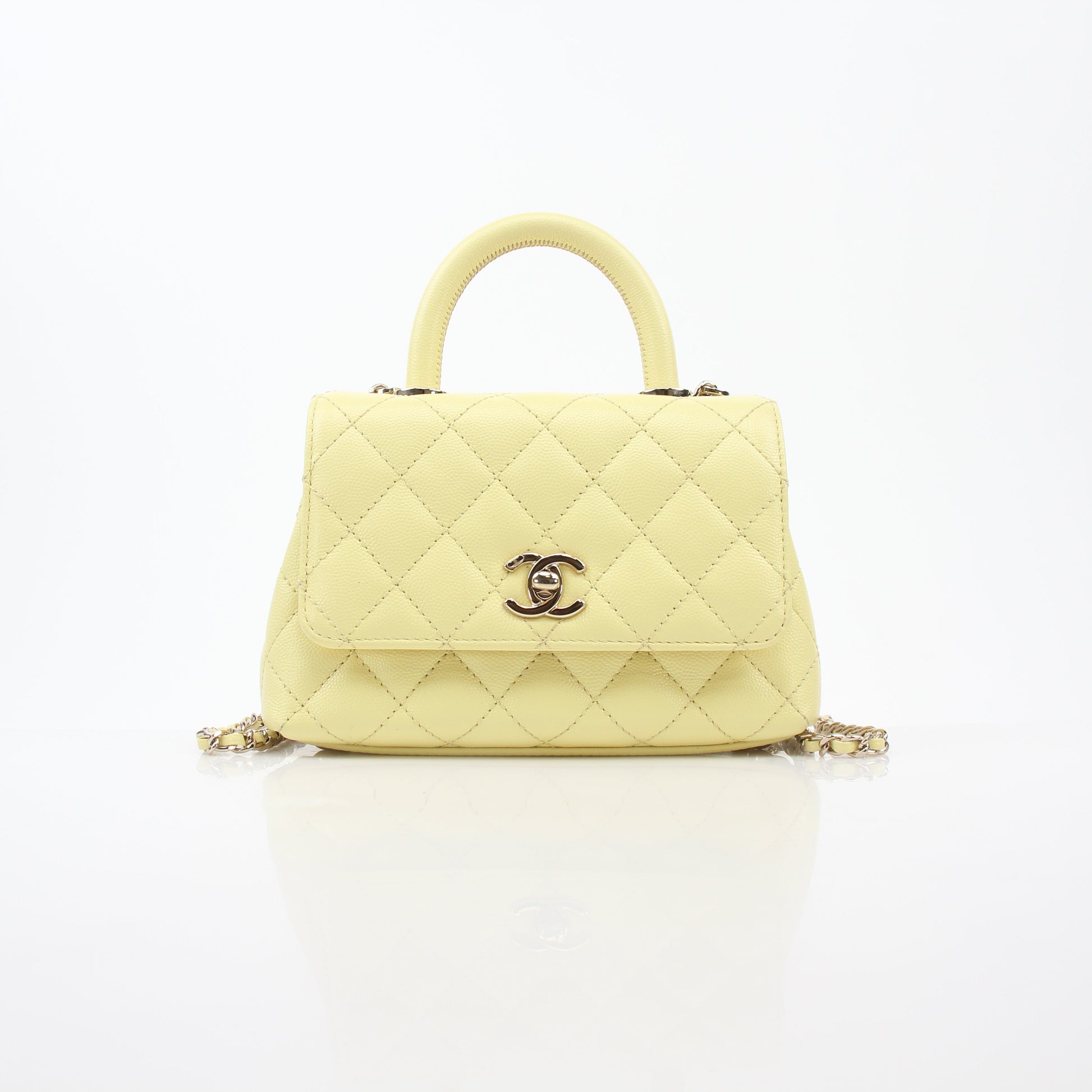 Chanel yellow mini Coco Handle flap handbag with gold chain and logo detail, stylish accessory for elegant occasions.