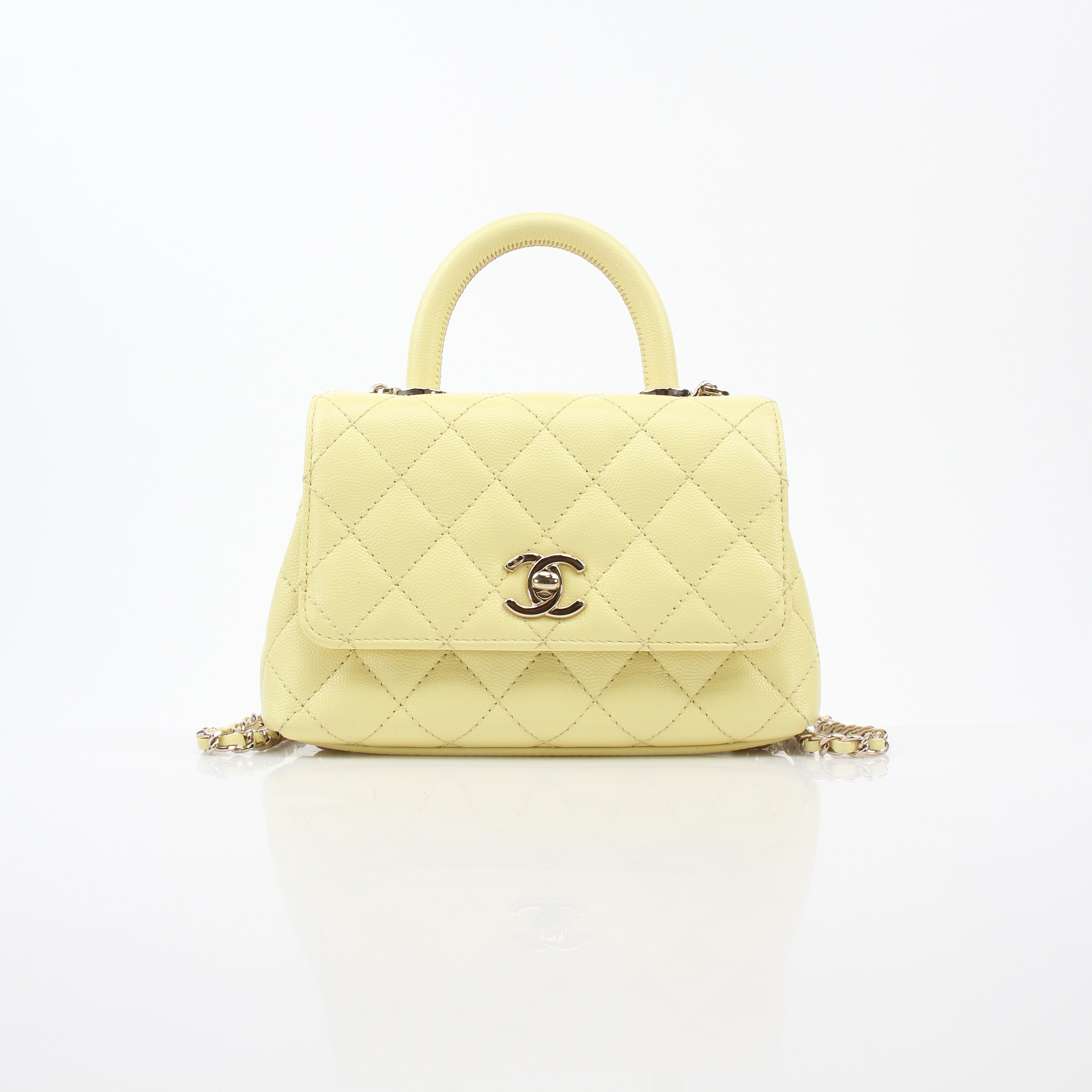 Chanel yellow mini Coco Handle flap handbag with gold chain and logo detail, stylish accessory for elegant occasions.
