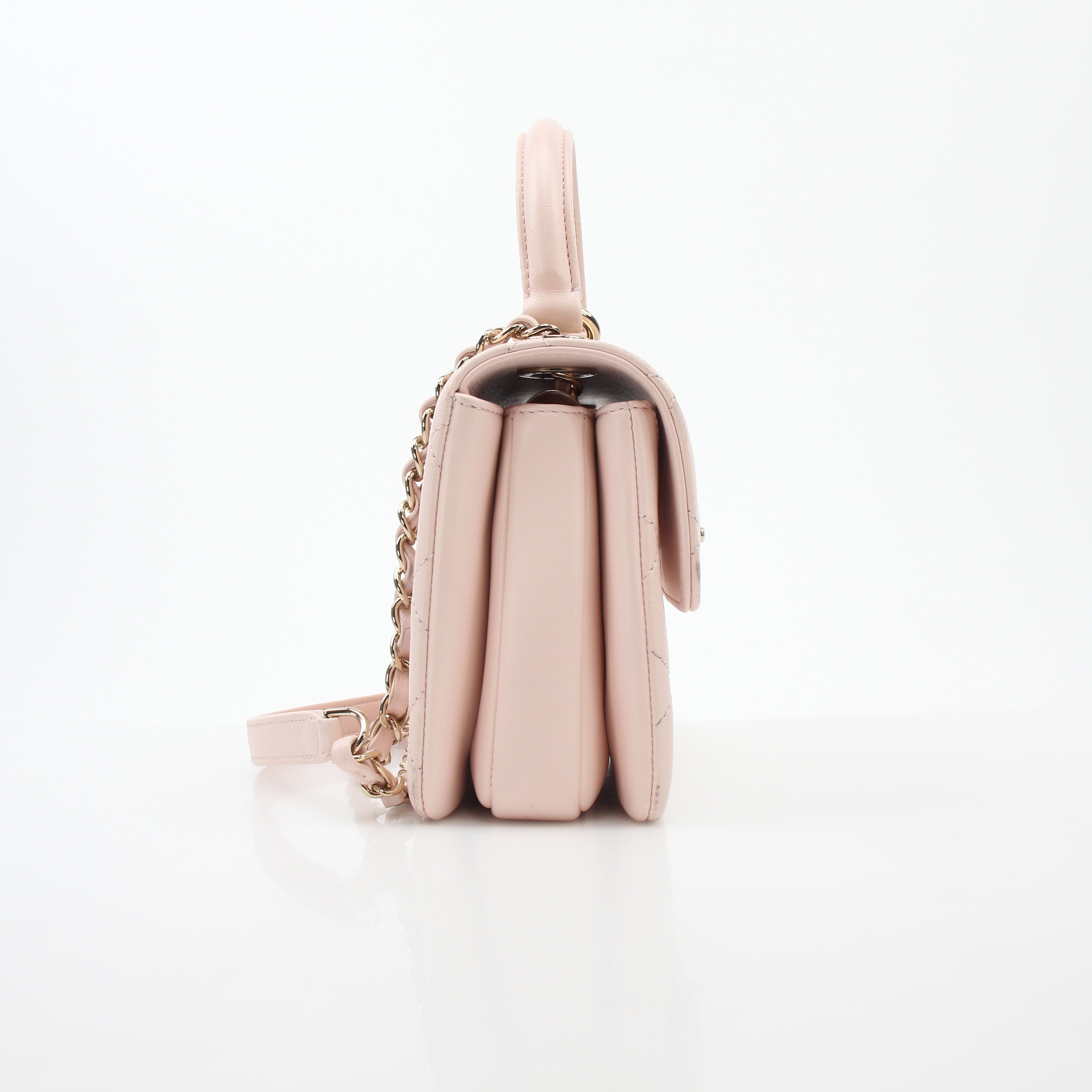 Pink Chanel small trend CC flap handbag with top handle, featuring gold accents and a quilted leather design.