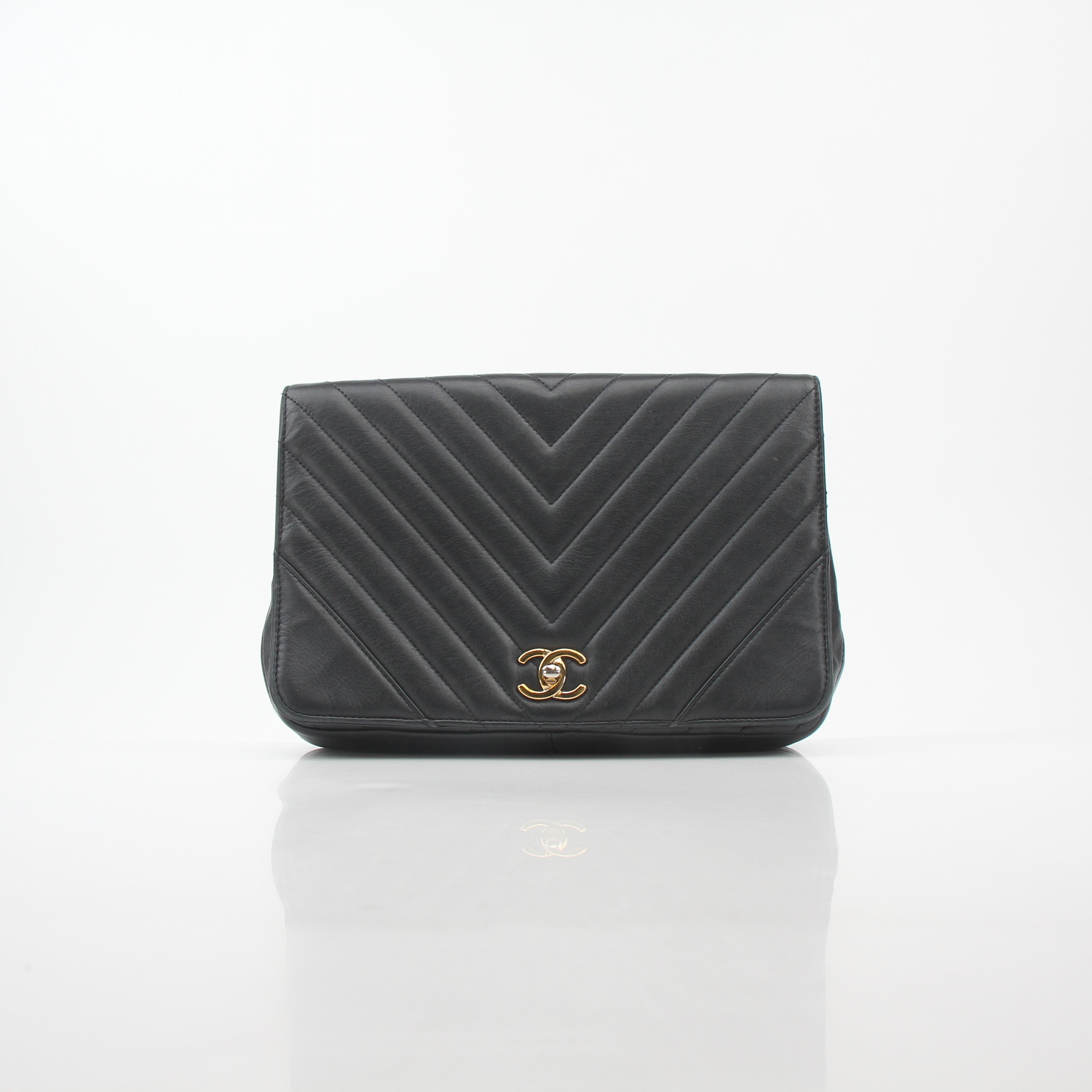 Chanel black chevron statement flap handbag with gold accents, featuring a structured design and signature quilted pattern.
