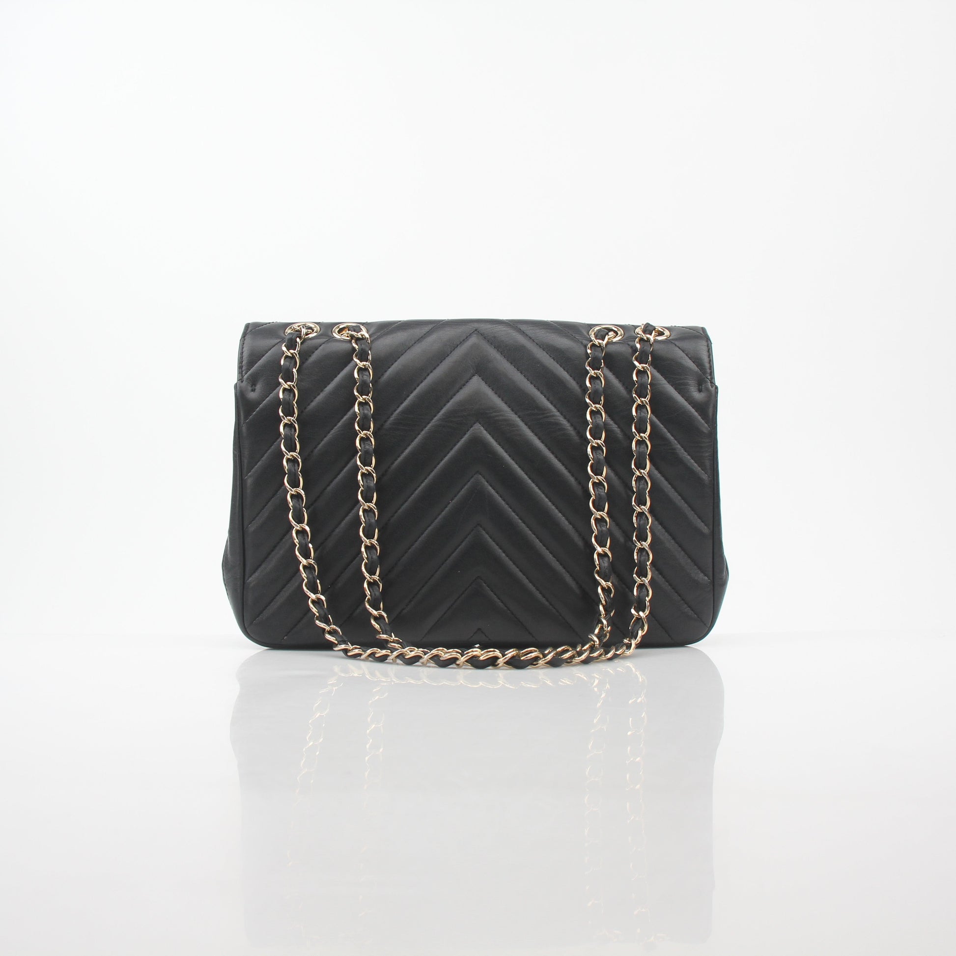 Chanel black chevron statement flap handbag with gold hardware, featuring a classic quilted design and chain strap.
