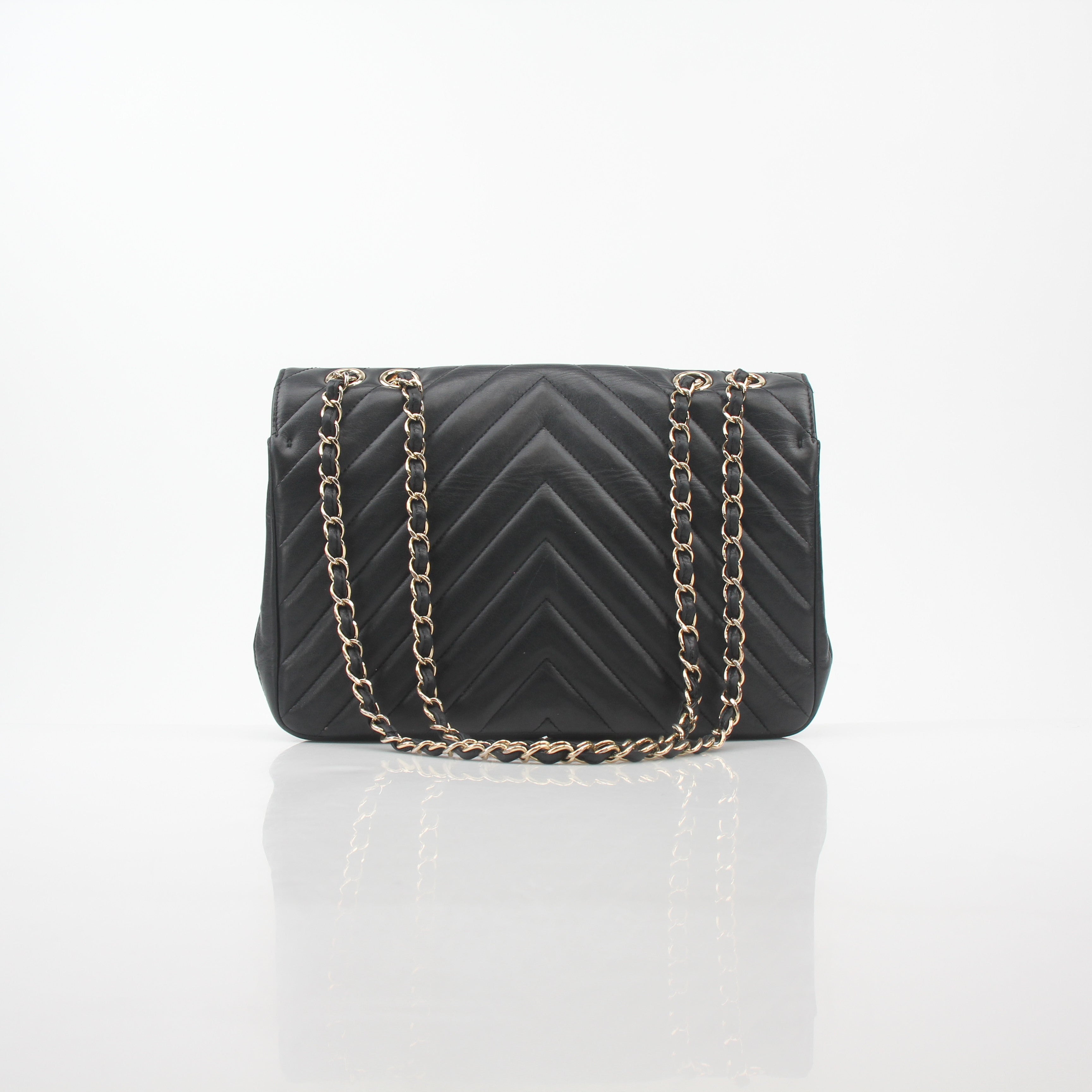 Chanel black chevron statement flap handbag with gold hardware, featuring a classic quilted design and chain strap.