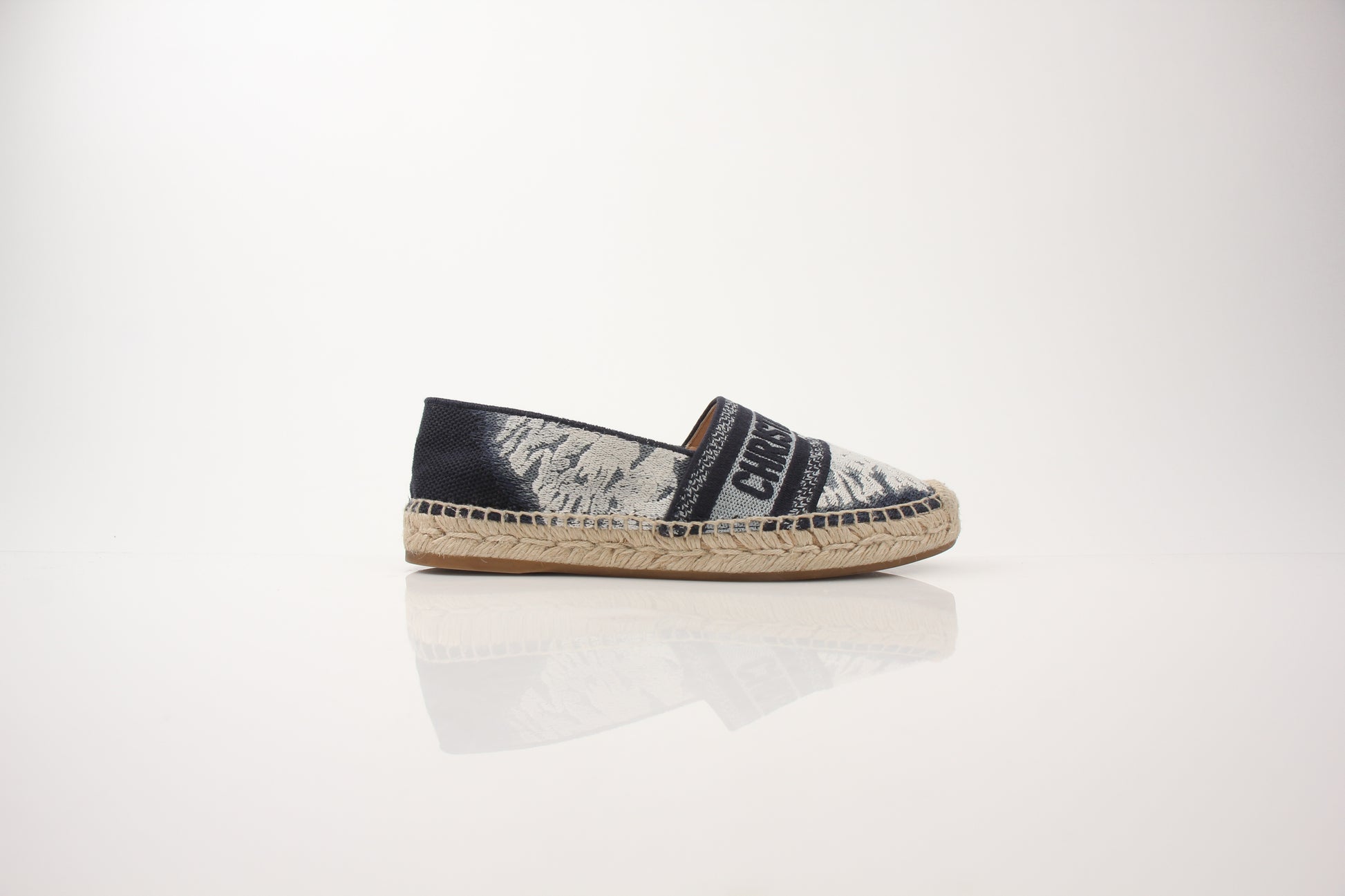 Christian Dior women’s Granville tie-dye espadrille flats on Gold & Beyond shoes display, featuring colorful woven fabric and flat sole.
