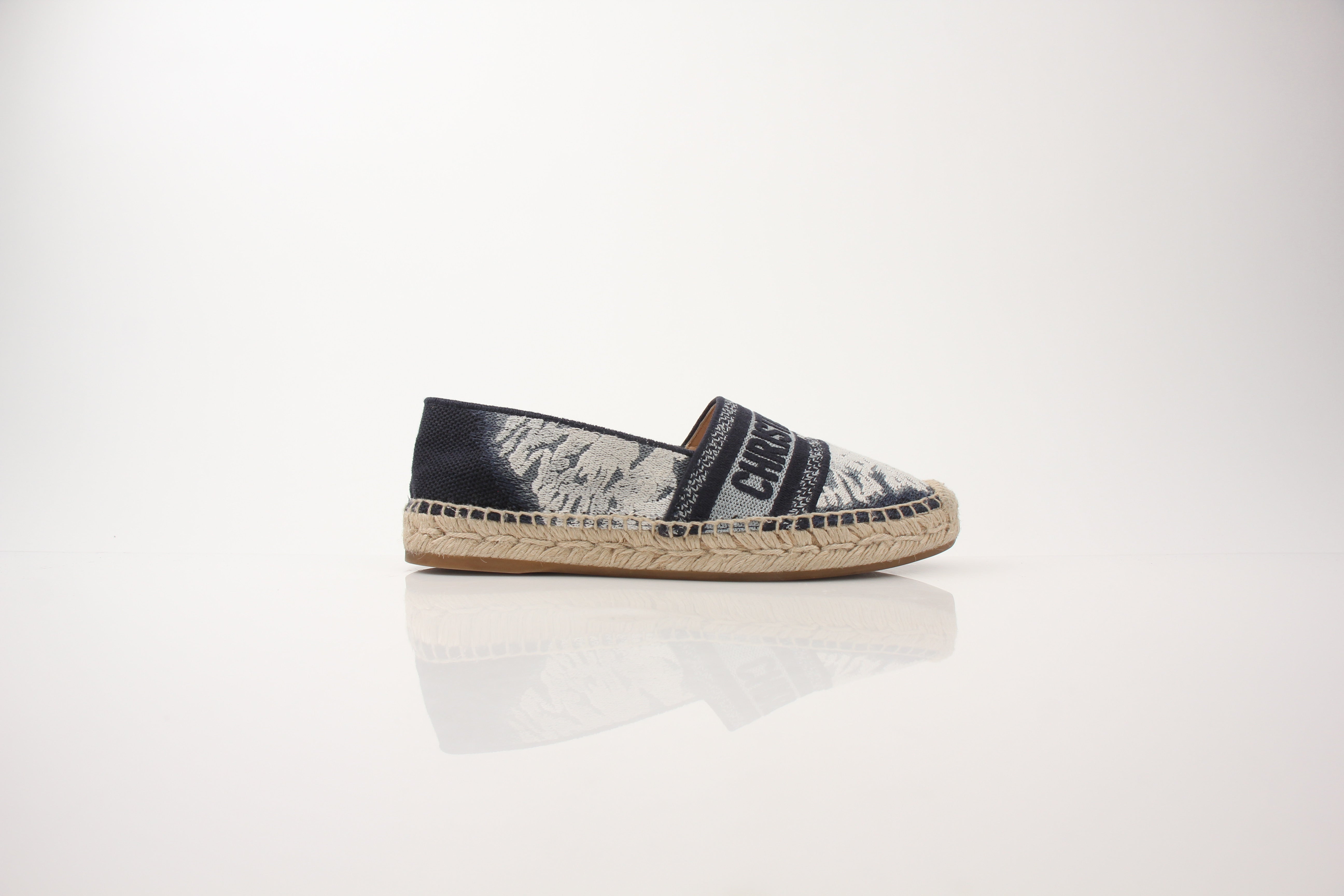 Christian Dior women’s Granville tie-dye espadrille flats on Gold & Beyond shoes display, featuring colorful woven fabric and flat sole.
