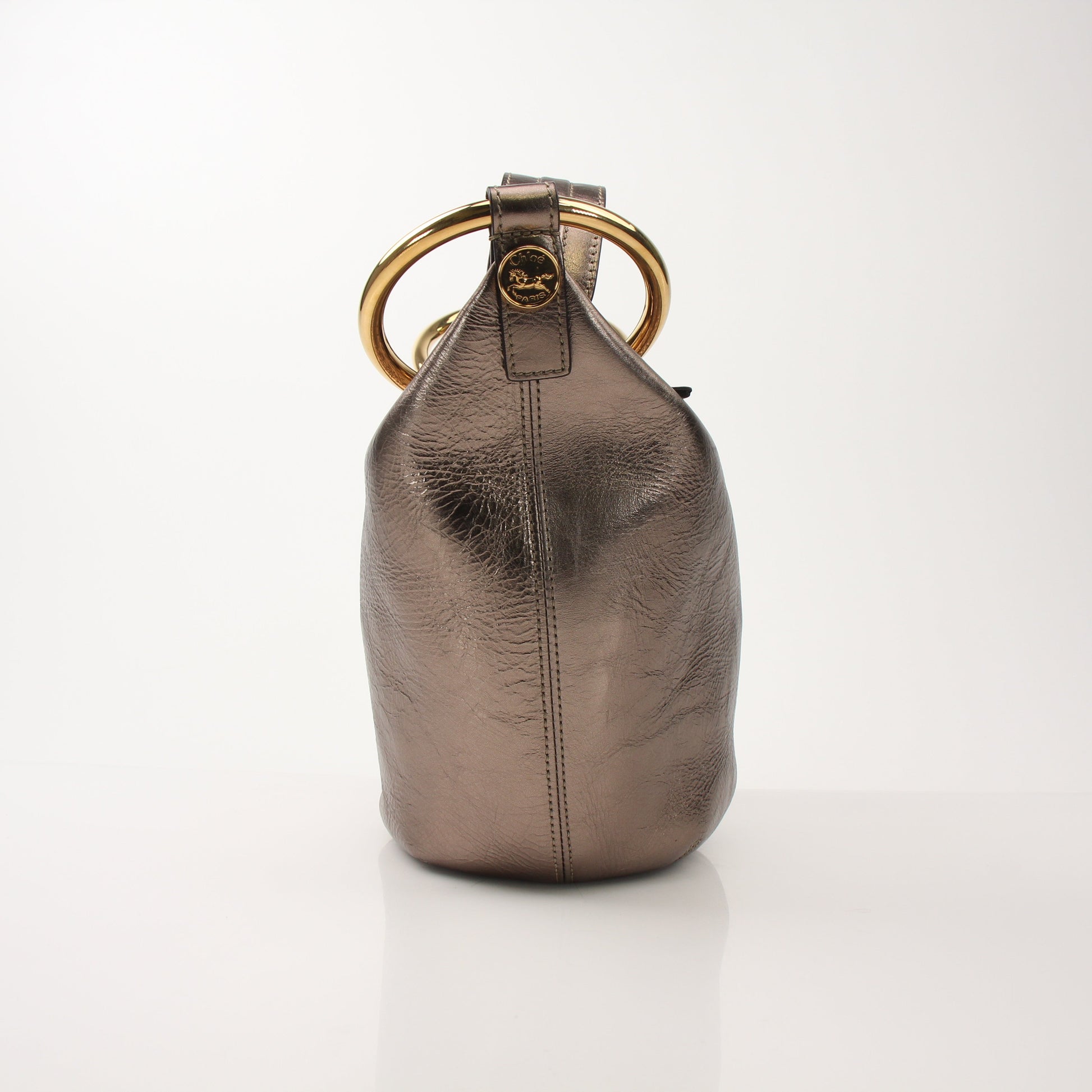 Gold & Beyond Chloé Nile metallic bucket handbag with bracelet handle, showing a stylish, textured design and gold-tone hardware.