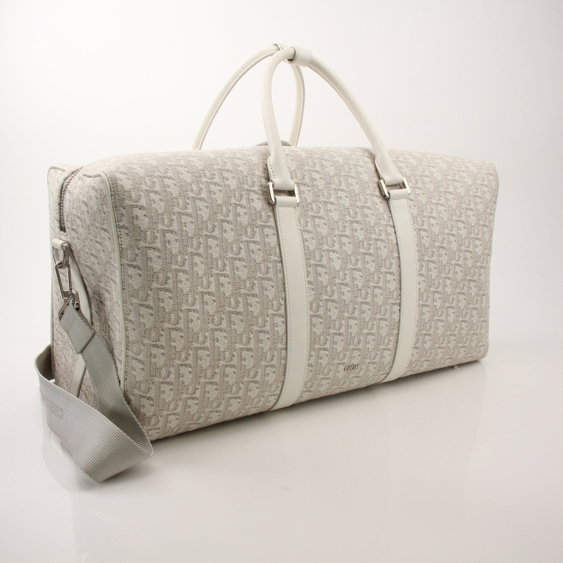 Christian Dior Lingot 50 duffle bag for travel, featuring sleek design and gold accents, displayed on a neutral background.
