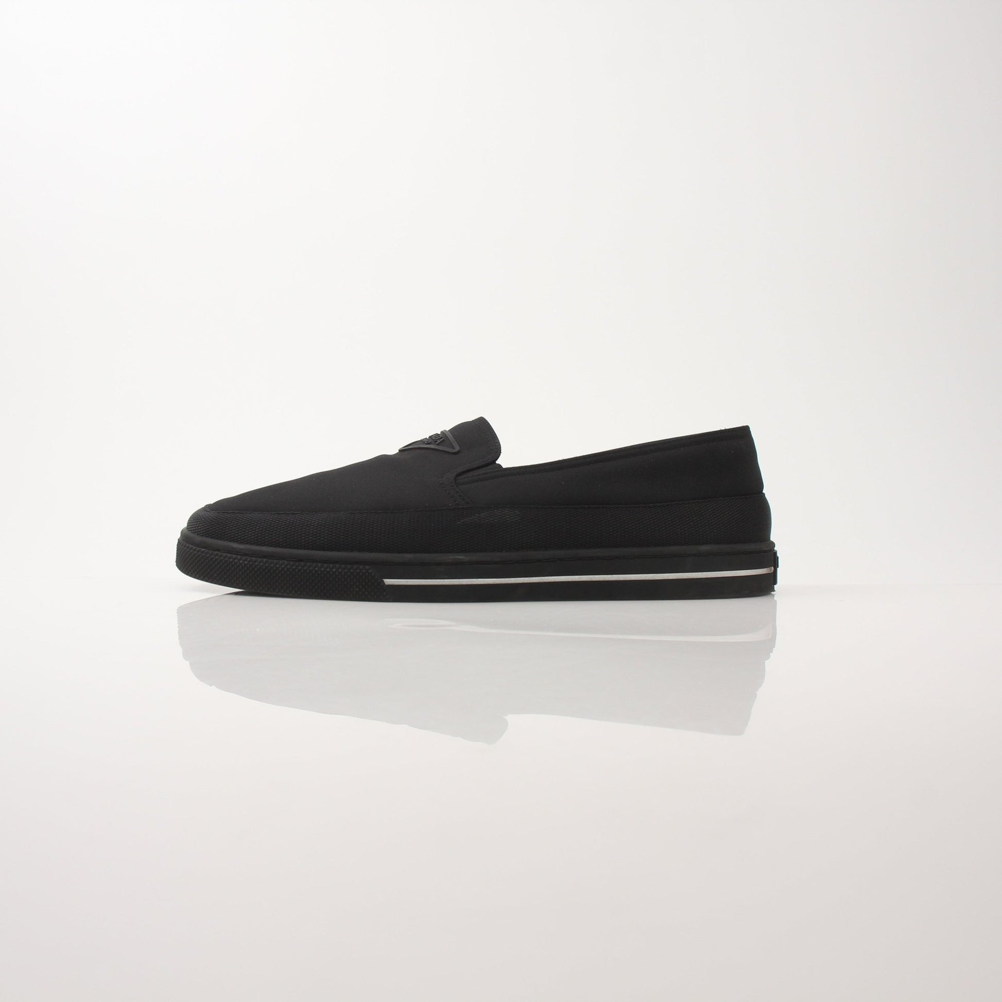 Gold & Beyond Prada men's triangle logo nylon slip-on loafers, showing sleek black shoes with logo detail and slip-on design.