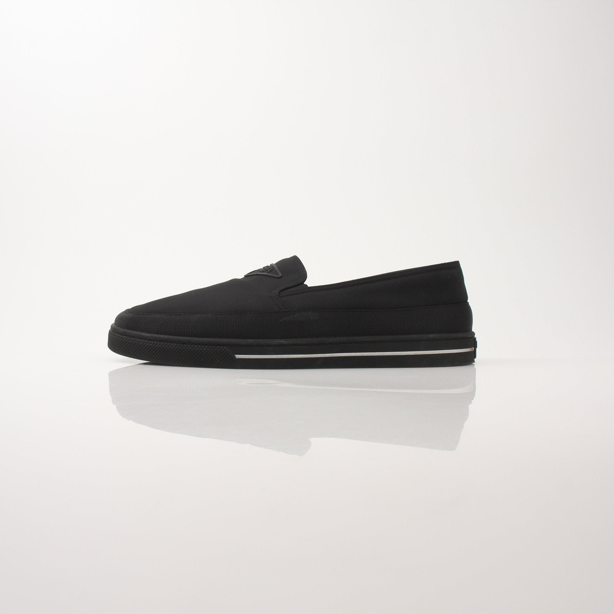 Gold & Beyond Prada men's triangle logo nylon slip-on loafers, showing sleek black shoes with logo detail and slip-on design.