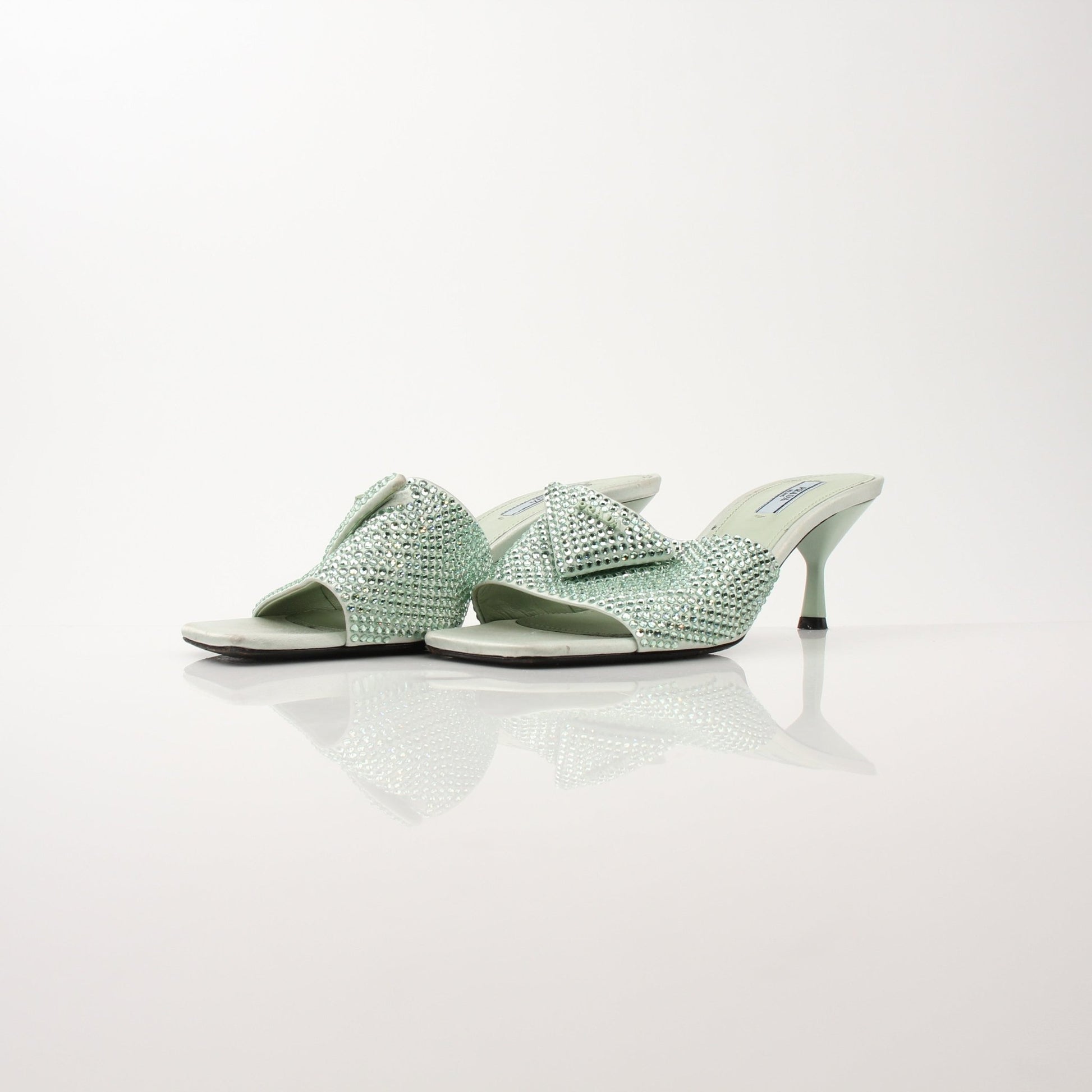 Prada women's crystal-embellished open-toe mules with stylish heels, featuring elegant design and sparkling details.