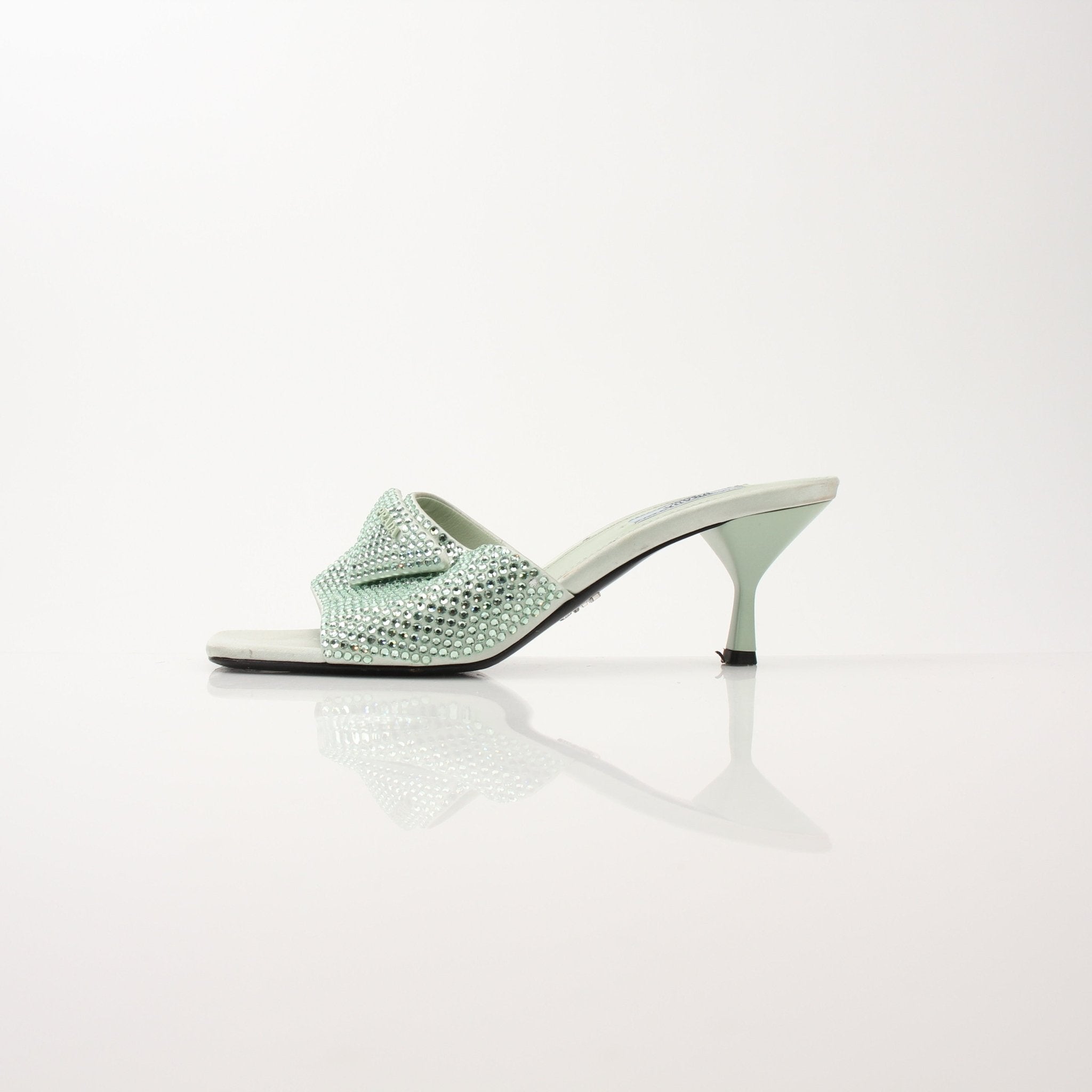Prada women’s crystal-embellished open-toe mules featuring elegant heels with sparkling accents and open-toe design.