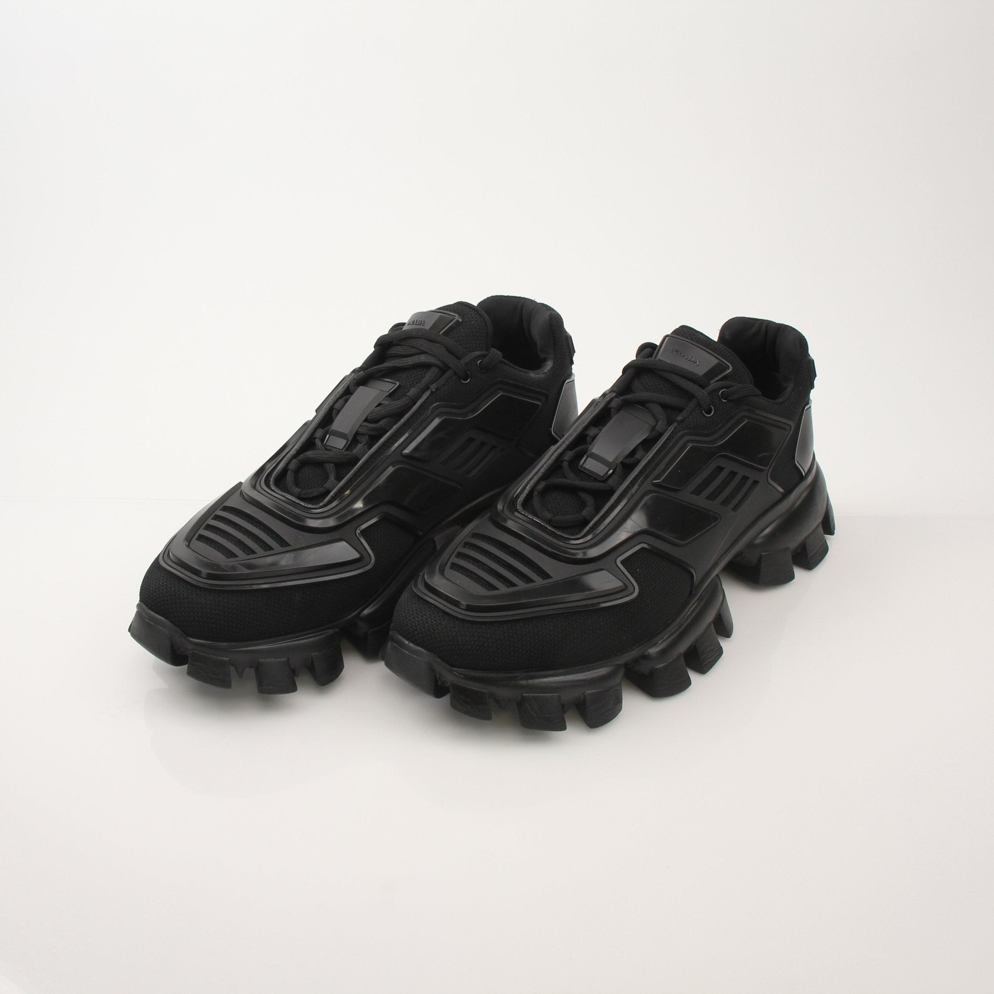 Prada Men’s Cloudbust Thunder knit fabric sneakers in white with black accents, showcasing sporty shoe design with textured knit material.