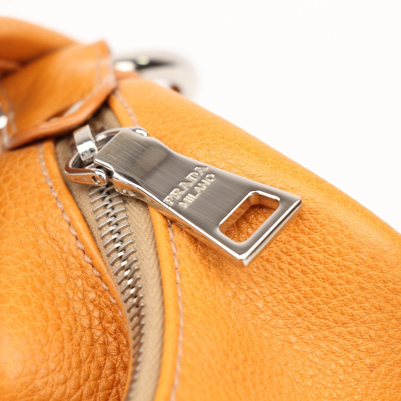 Prada orange Daino leather handbag with sleek design and sturdy handles, showcasing elegant craftsmanship and vibrant color.