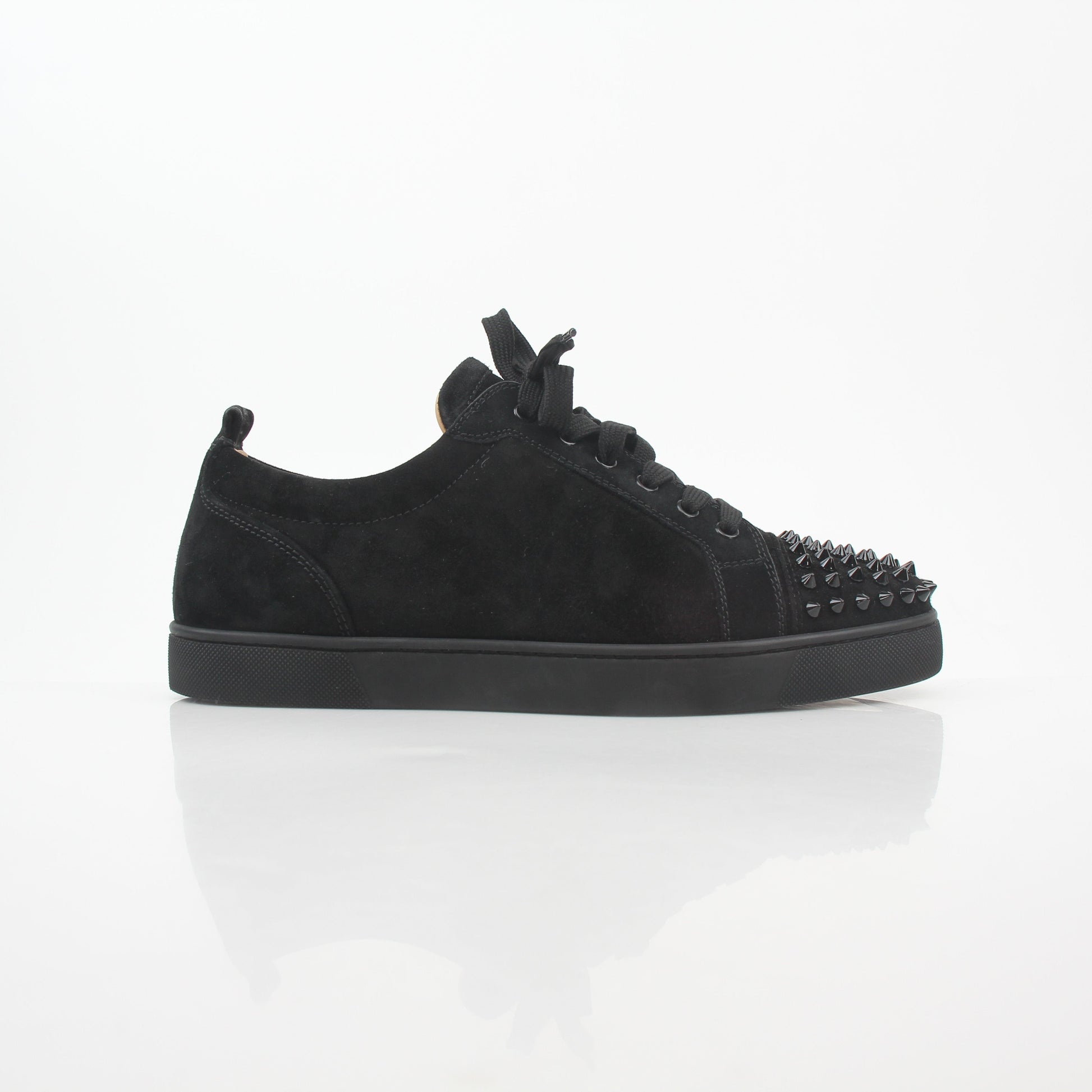 Black Christian Louboutin Louis Junior Spikes low-top sneakers with metal spikes and signature red sole, styled with casual clothing.