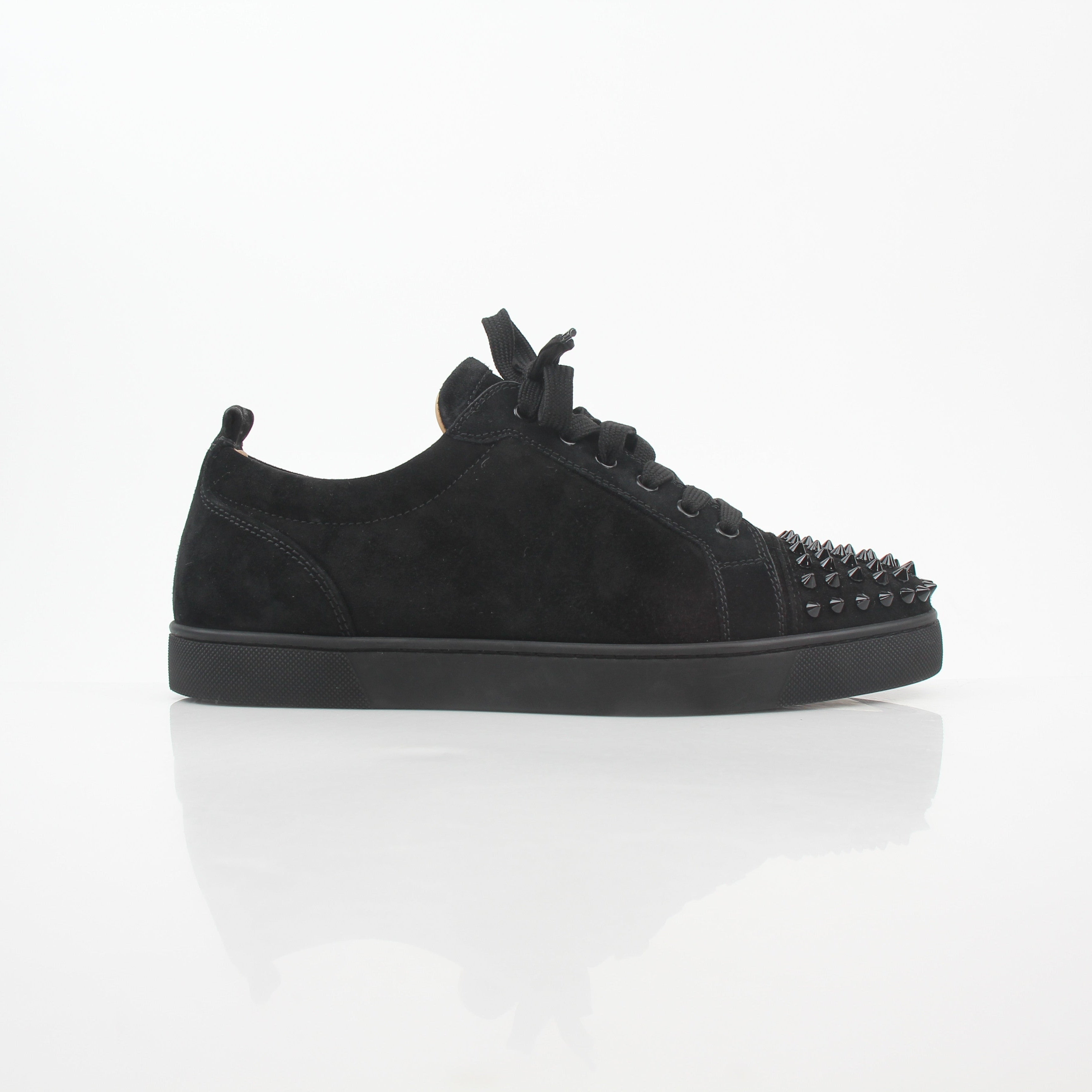 Black Christian Louboutin Louis Junior Spikes low-top sneakers with metal spikes and signature red sole, styled with casual clothing.