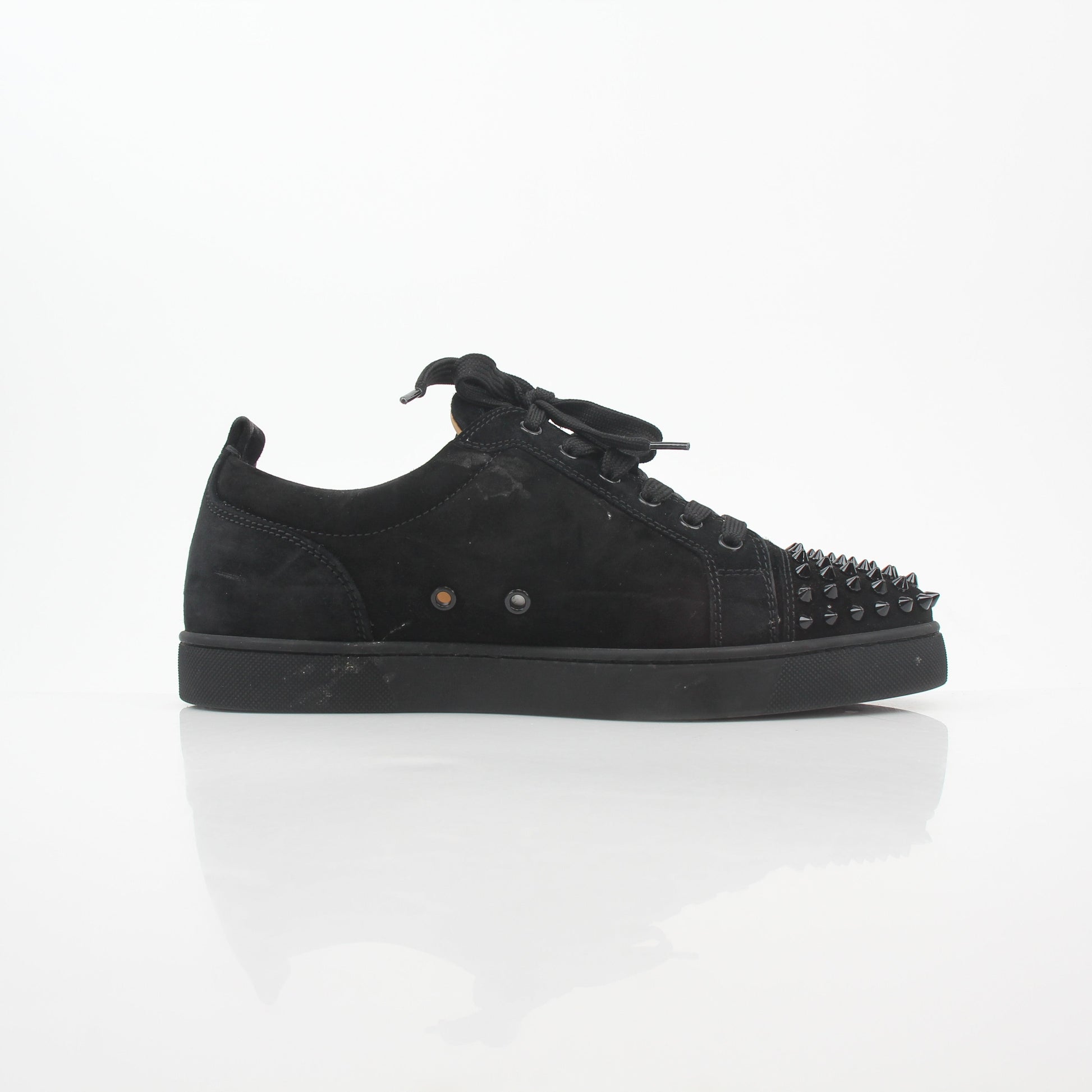 Black Christian Louboutin Louis Junior Spikes low-top sneakers with gold accents and spike details, showcased in a casual shoe display.