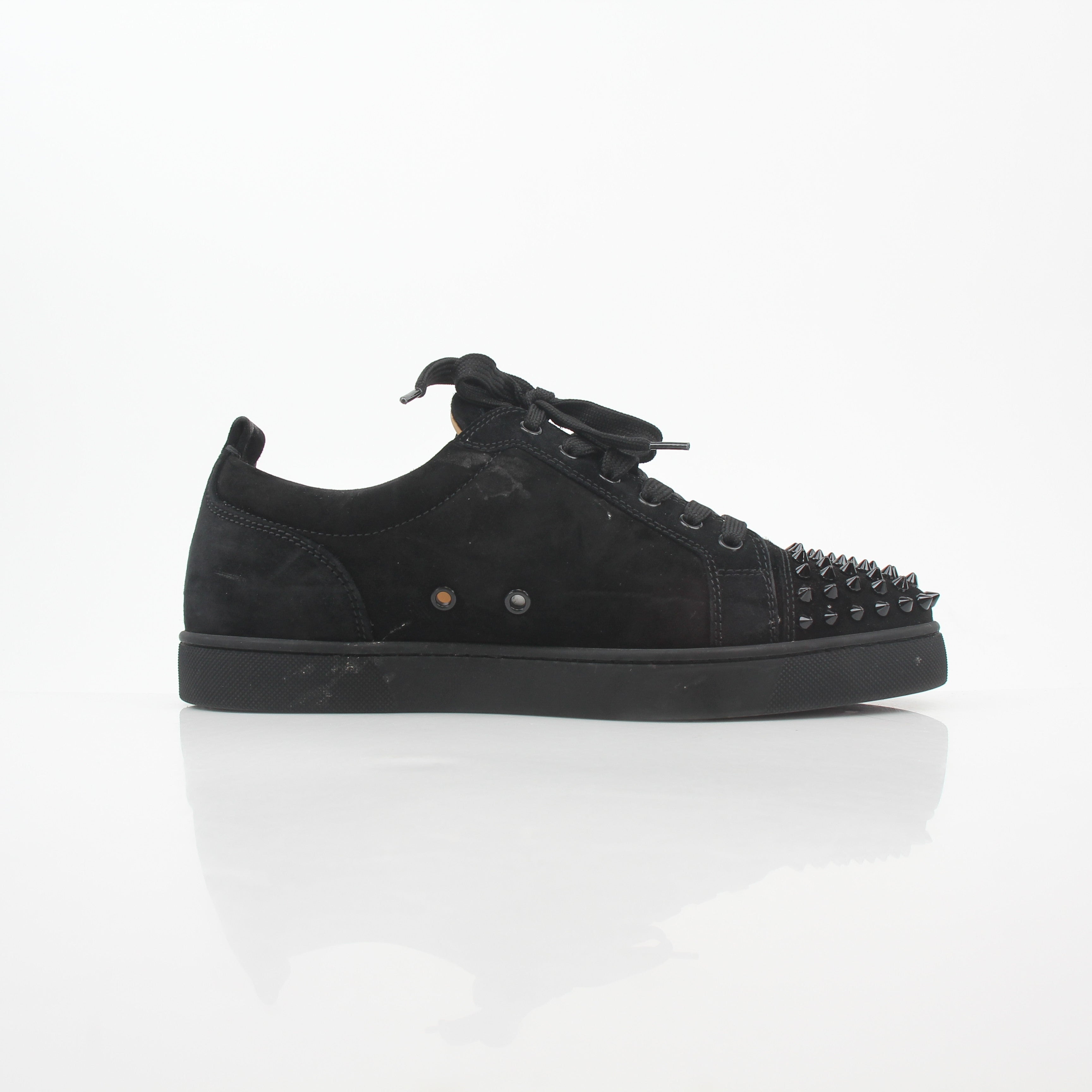 Black Christian Louboutin Louis Junior Spikes low-top sneakers with gold accents and spike details, showcased in a casual shoe display.
