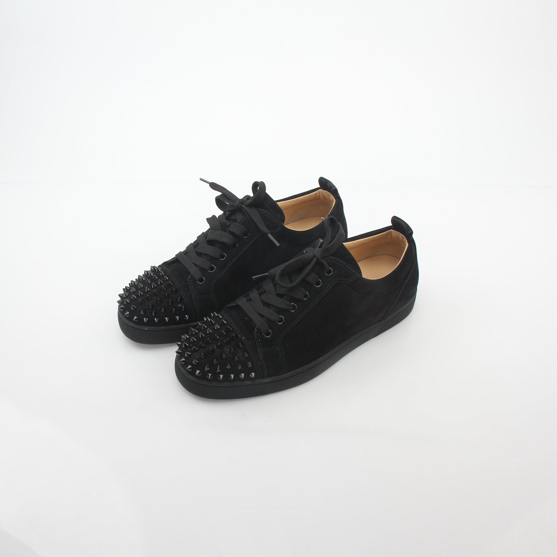 Black Christian Louboutin Louis Junior Spikes low-top sneakers with gold accents and spike details, displayed on a plain background.