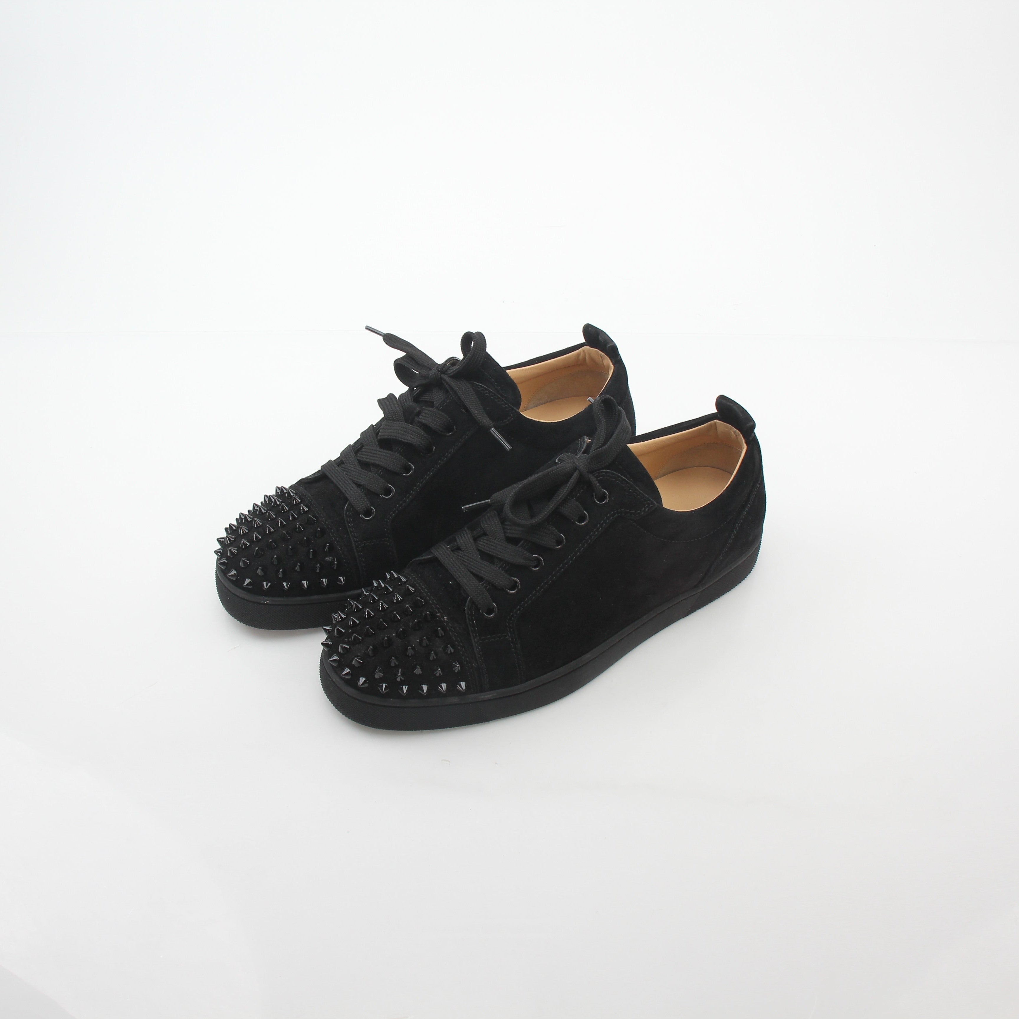 Black Christian Louboutin Louis Junior Spikes low-top sneakers with gold accents and spike details, displayed on a plain background.