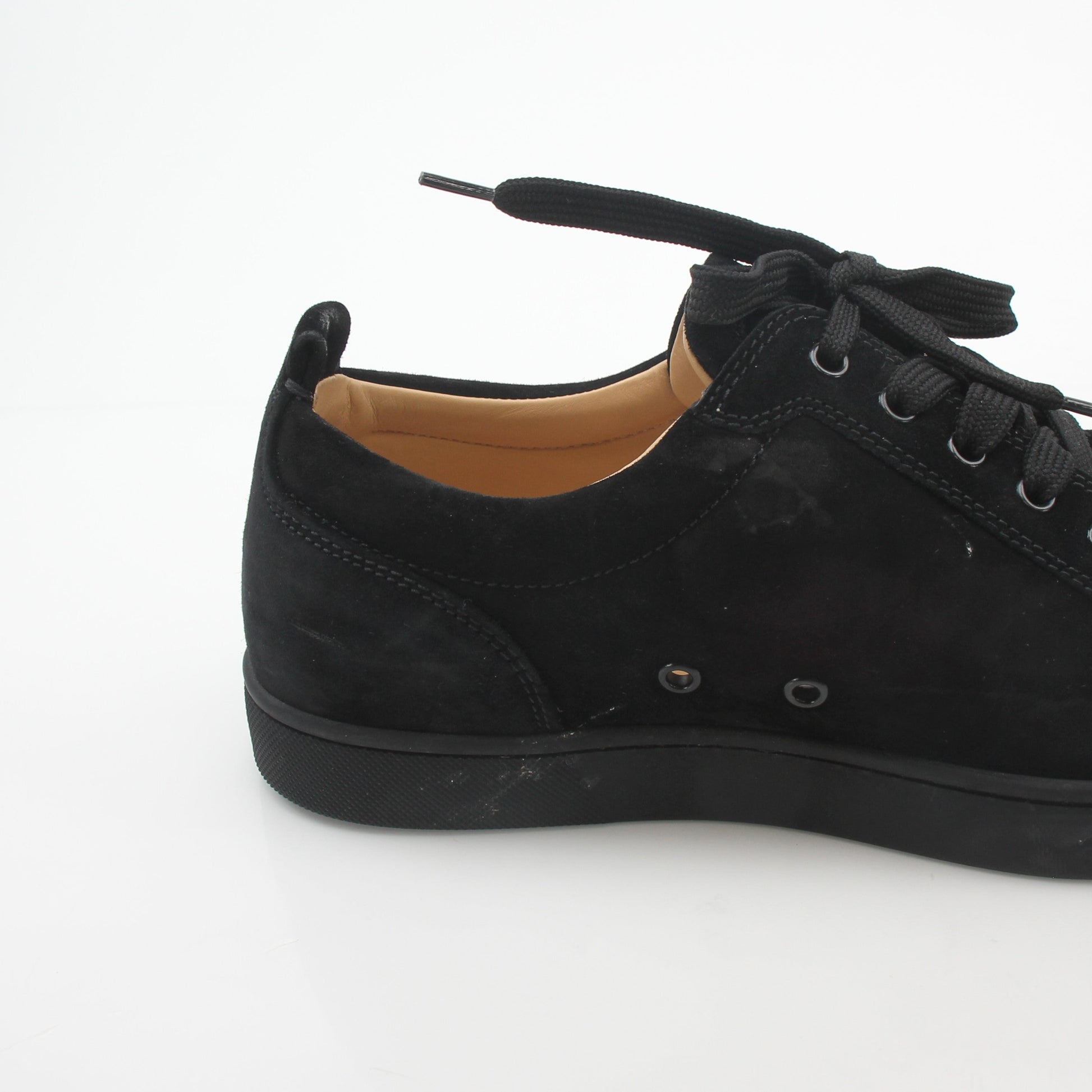 Christian Louboutin Black Louis Junior Spikes low-top sneakers featuring spikes and sleek design, worn on a model's feet.