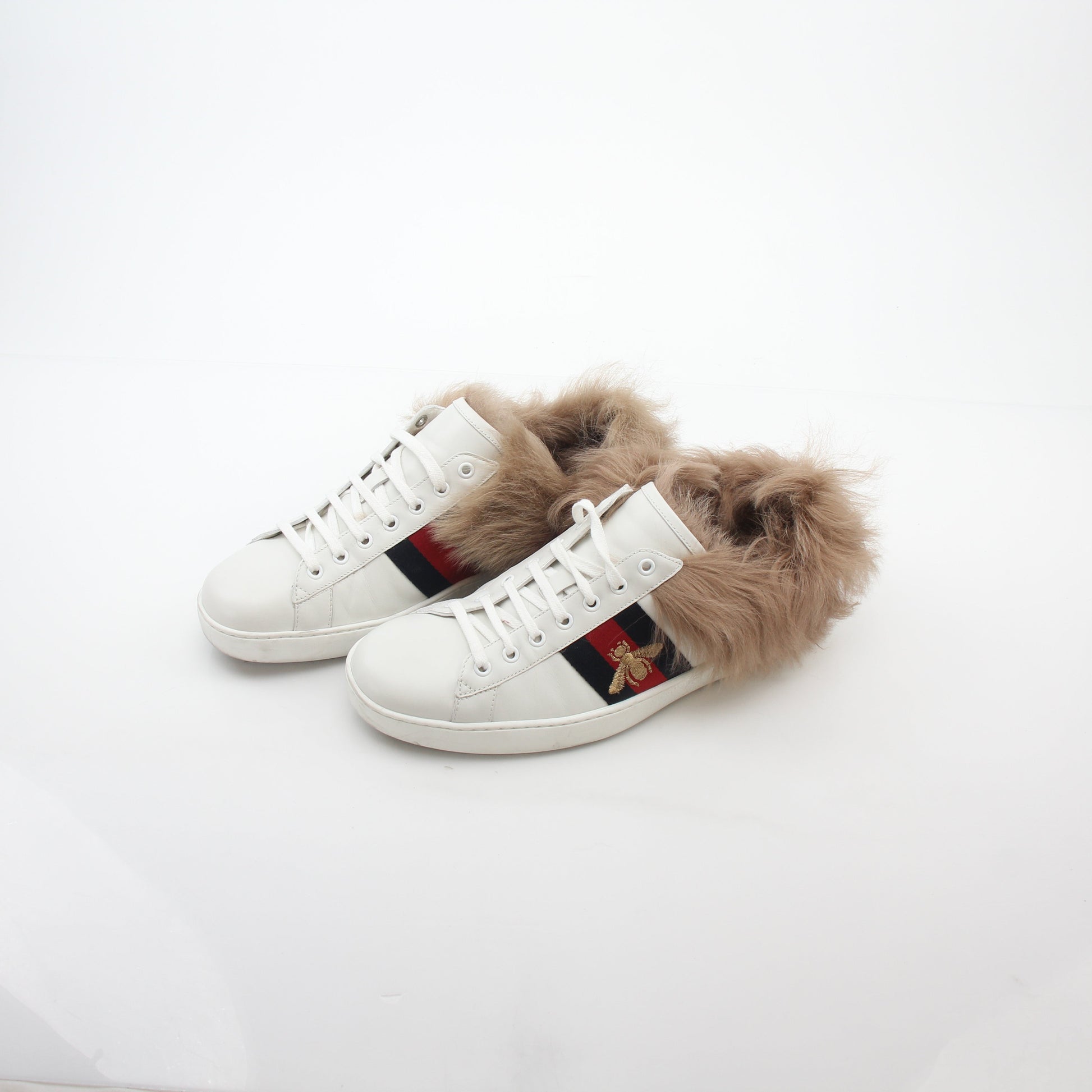 Gucci White Ace embroidered bee fur low-top sneakers with gold accents and logo details, displayed on a plain background.