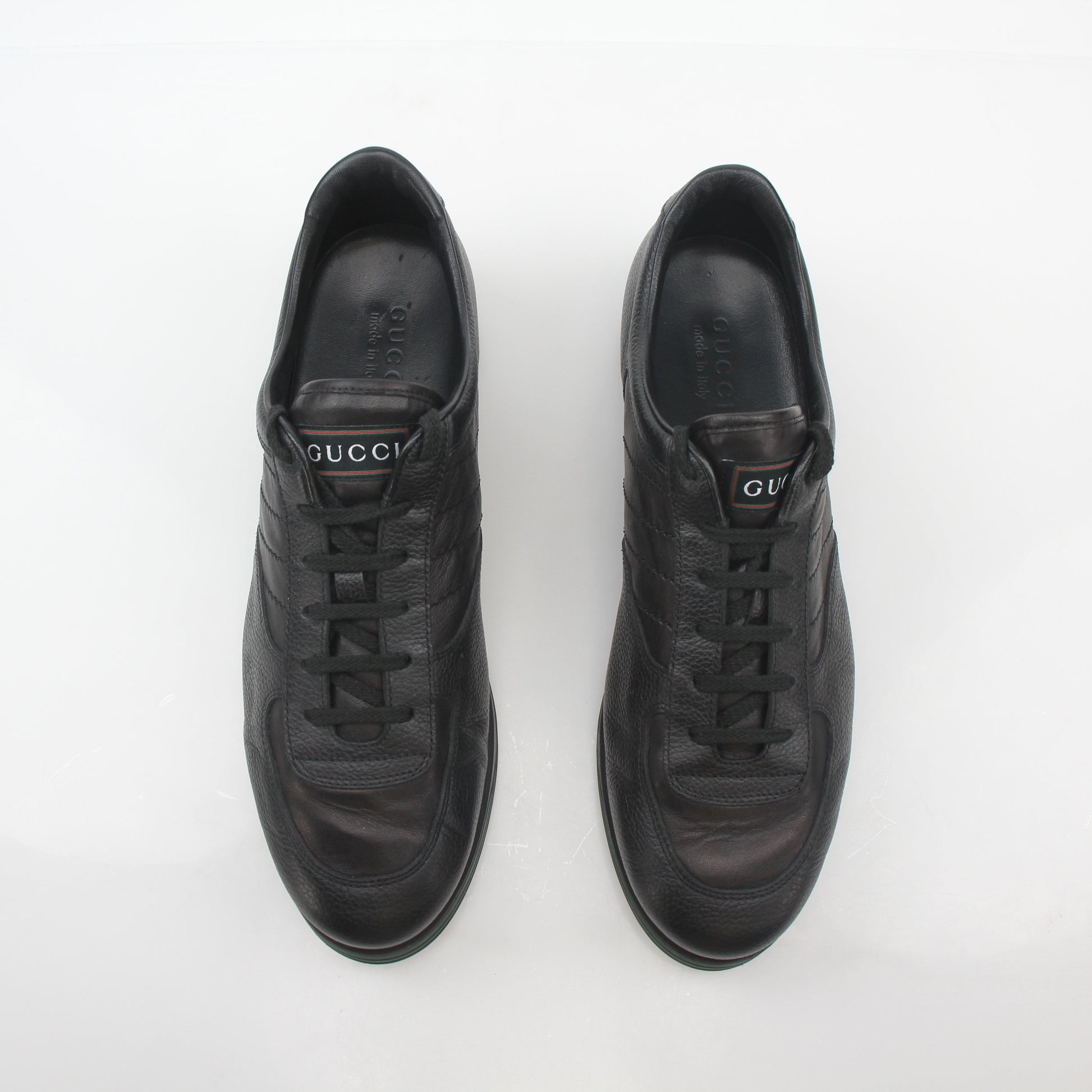 Gold & Beyond Gucci Black Tennis 1984 low-top sneakers, showcasing sleek black leather shoes with white rubber soles and iconic branding.