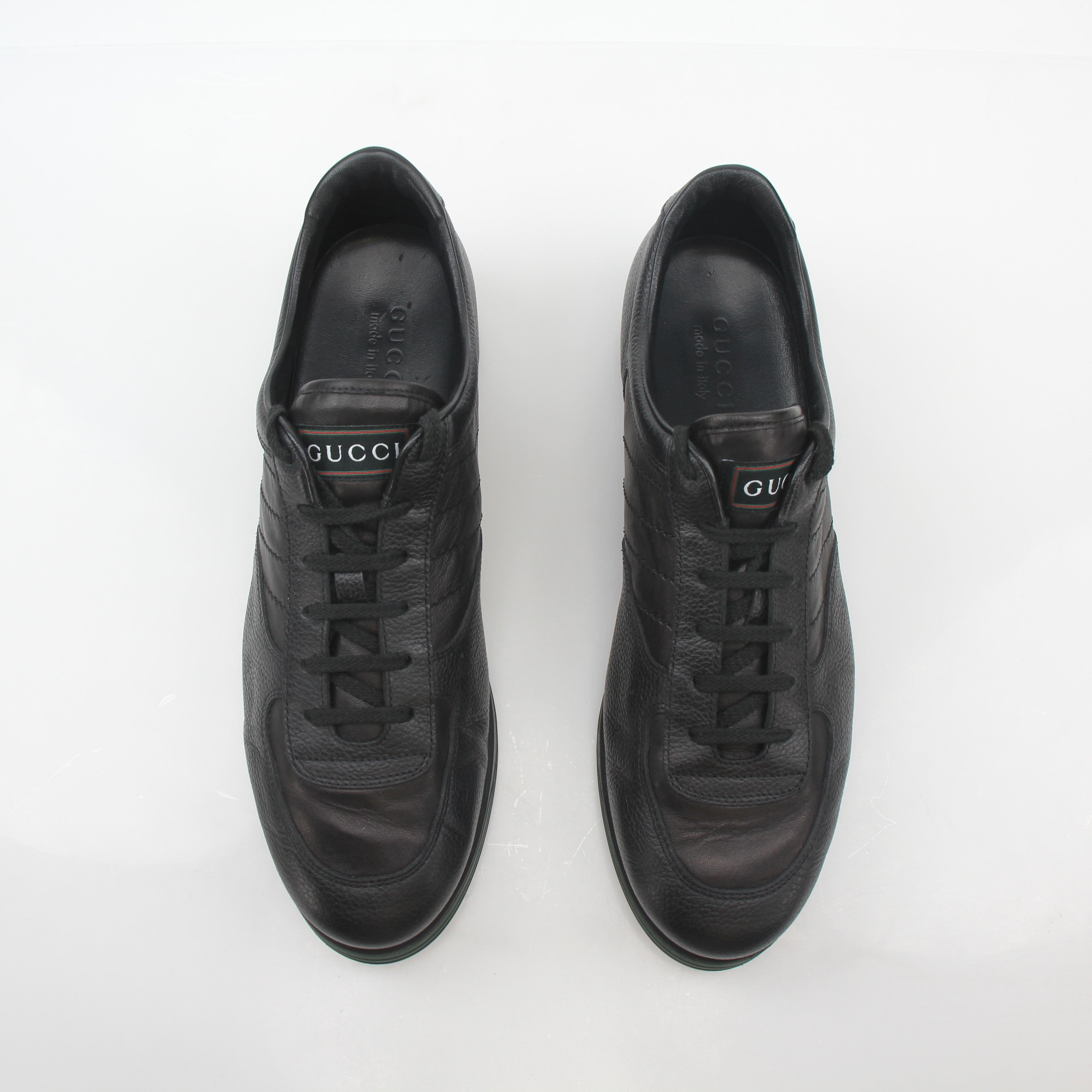 Gold & Beyond Gucci Black Tennis 1984 low-top sneakers, showcasing sleek black leather shoes with white rubber soles and iconic branding.
