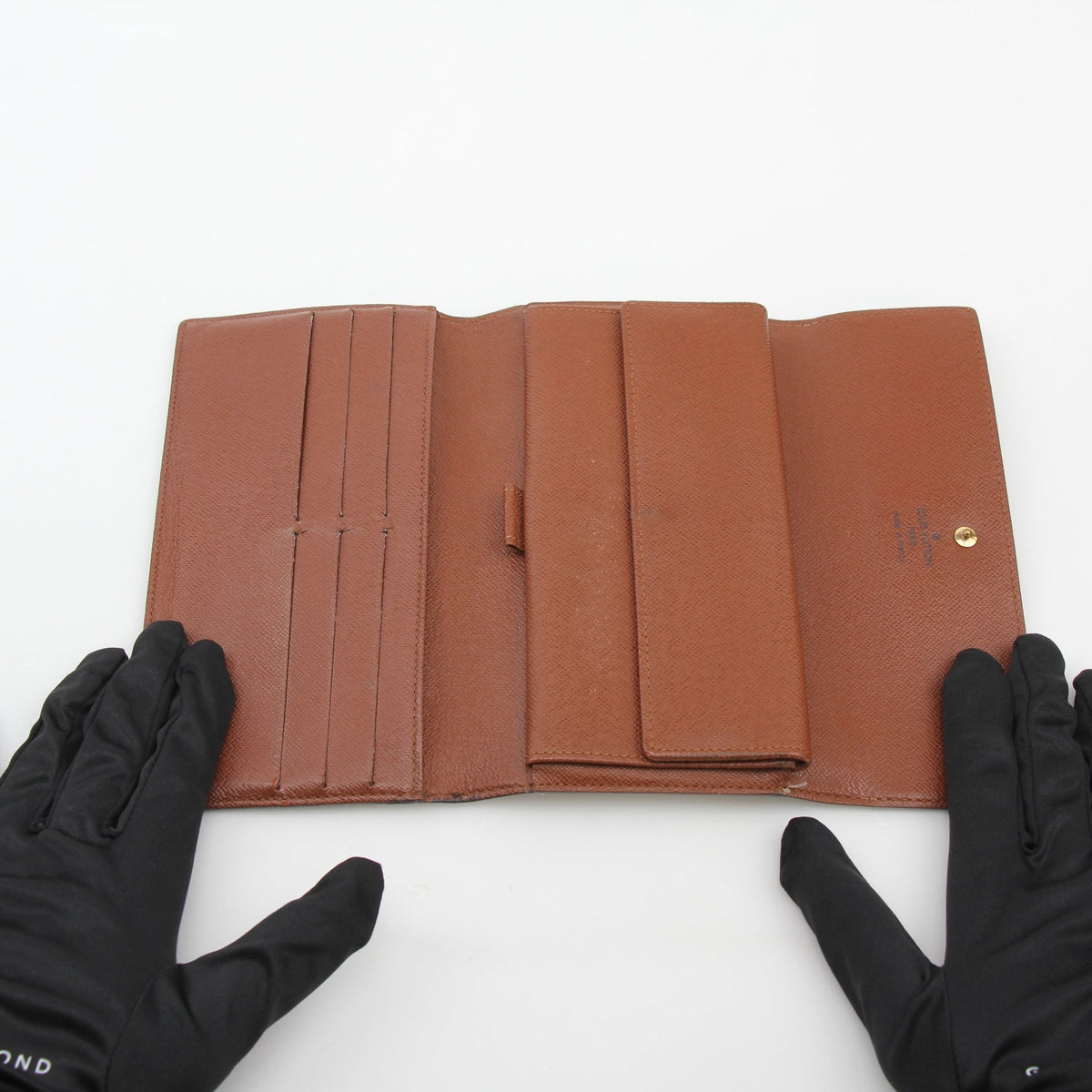 Louis Vuitton brown monogram portefeuille international wallet with gold accents, featuring multiple card slots and a sleek design.
