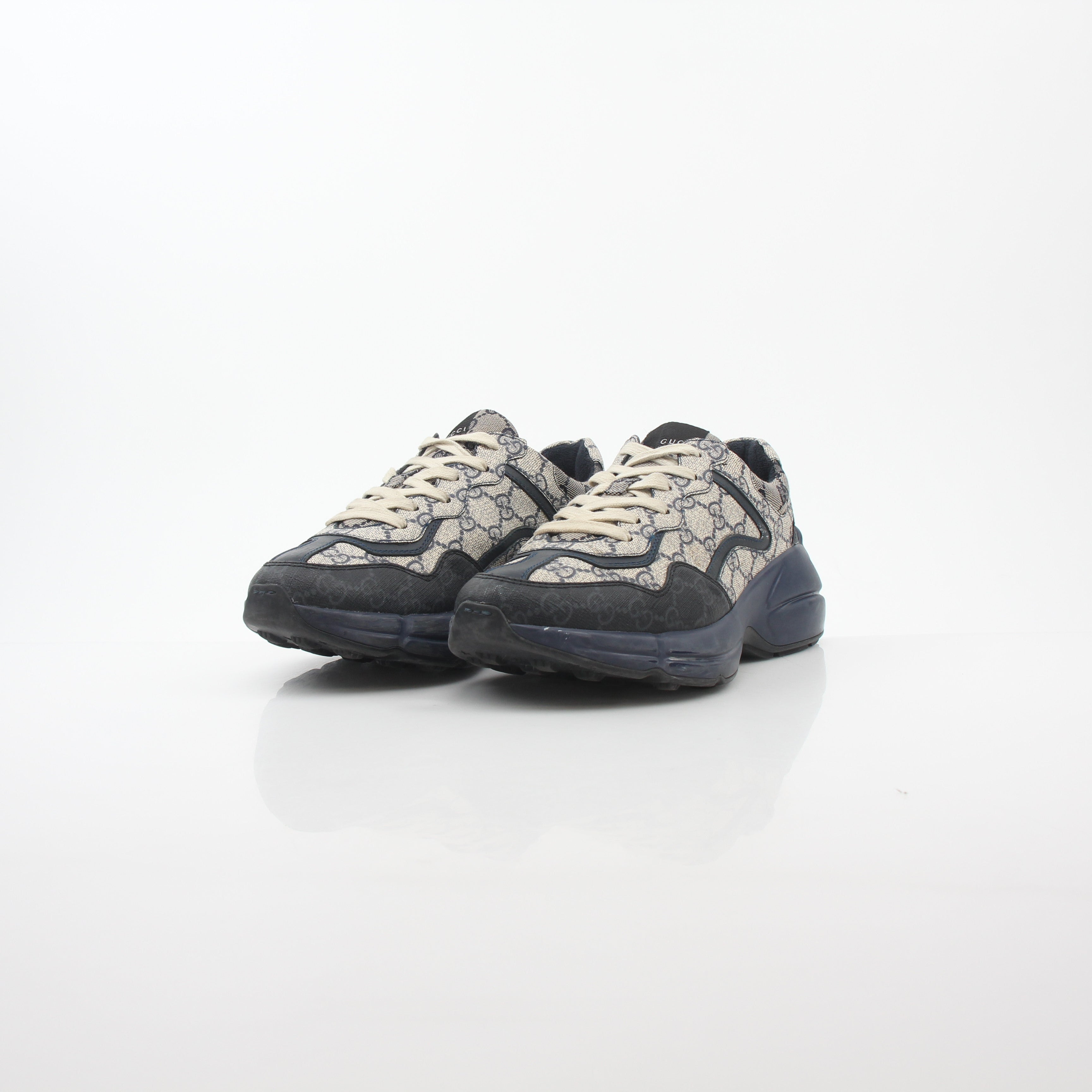 Gucci Rhyton GG Supreme Canvas Sneakers with white rubber soles and gold accents, displayed on a plain background.