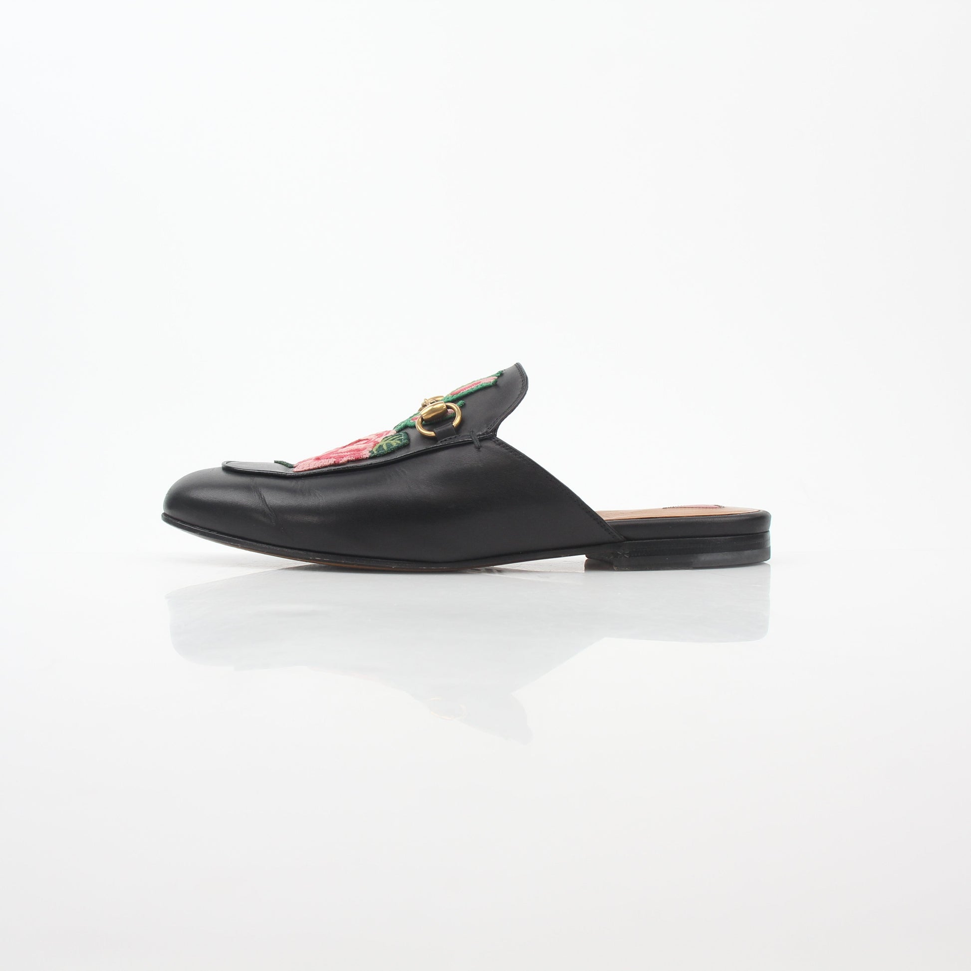 Black Gucci Princetown leather mules with rose embroidery, featuring a slip-on shoe design and elegant craftsmanship.