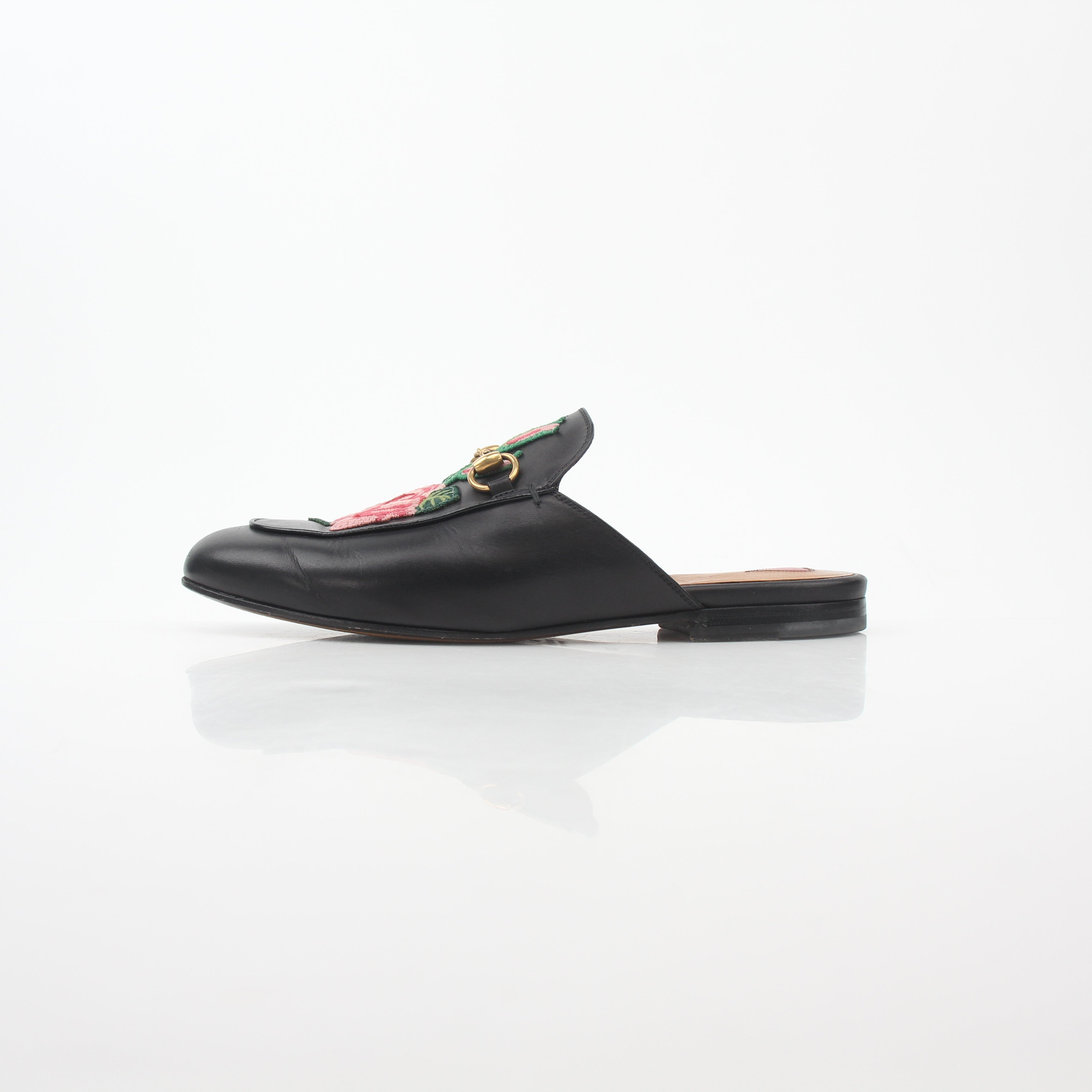 Black Gucci Princetown leather mules with rose embroidery, featuring a slip-on shoe design and elegant craftsmanship.