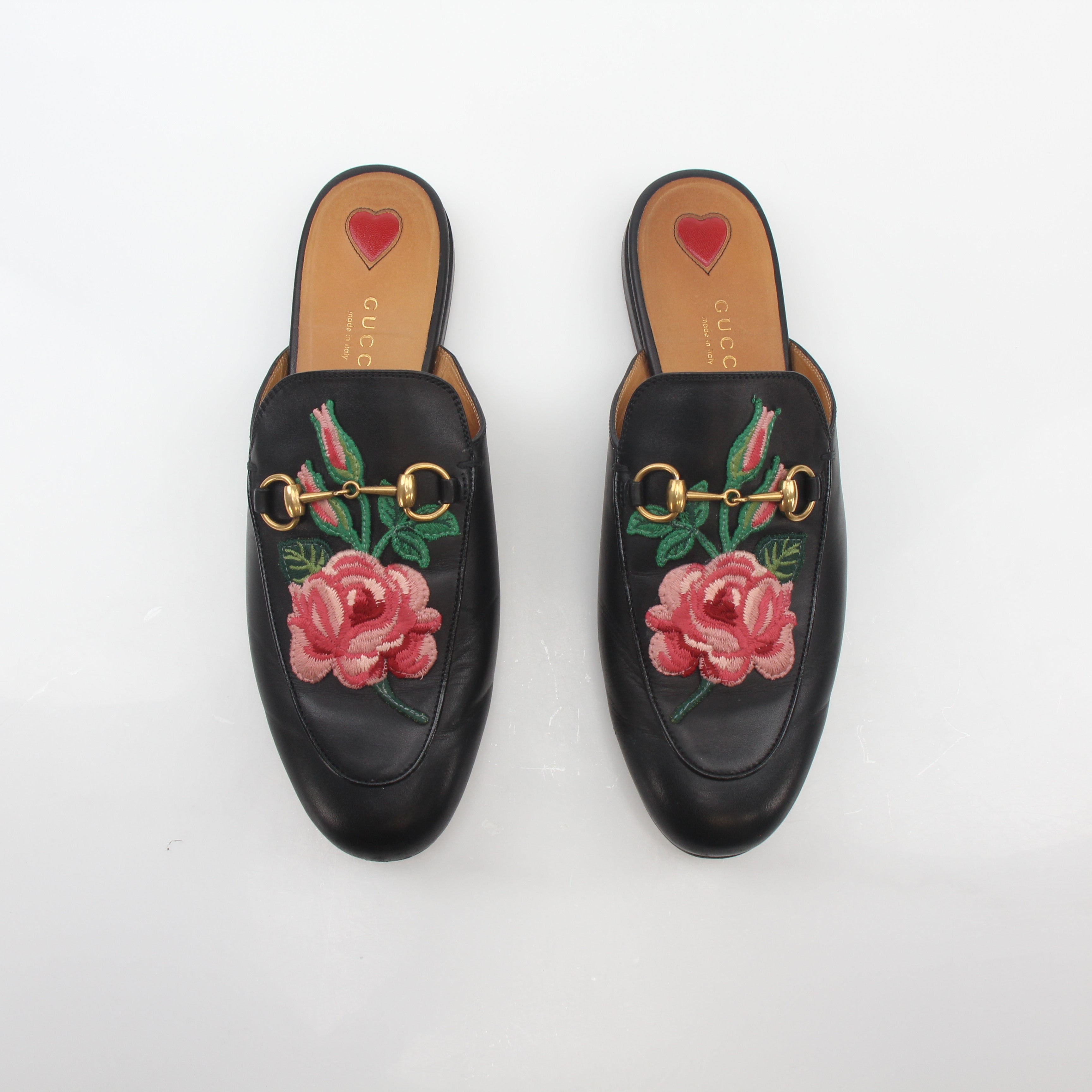 Black Gucci Princetown leather mules with rose embroidery, showcasing a stylish slip-on shoe with a pointed toe and textured leather finish.