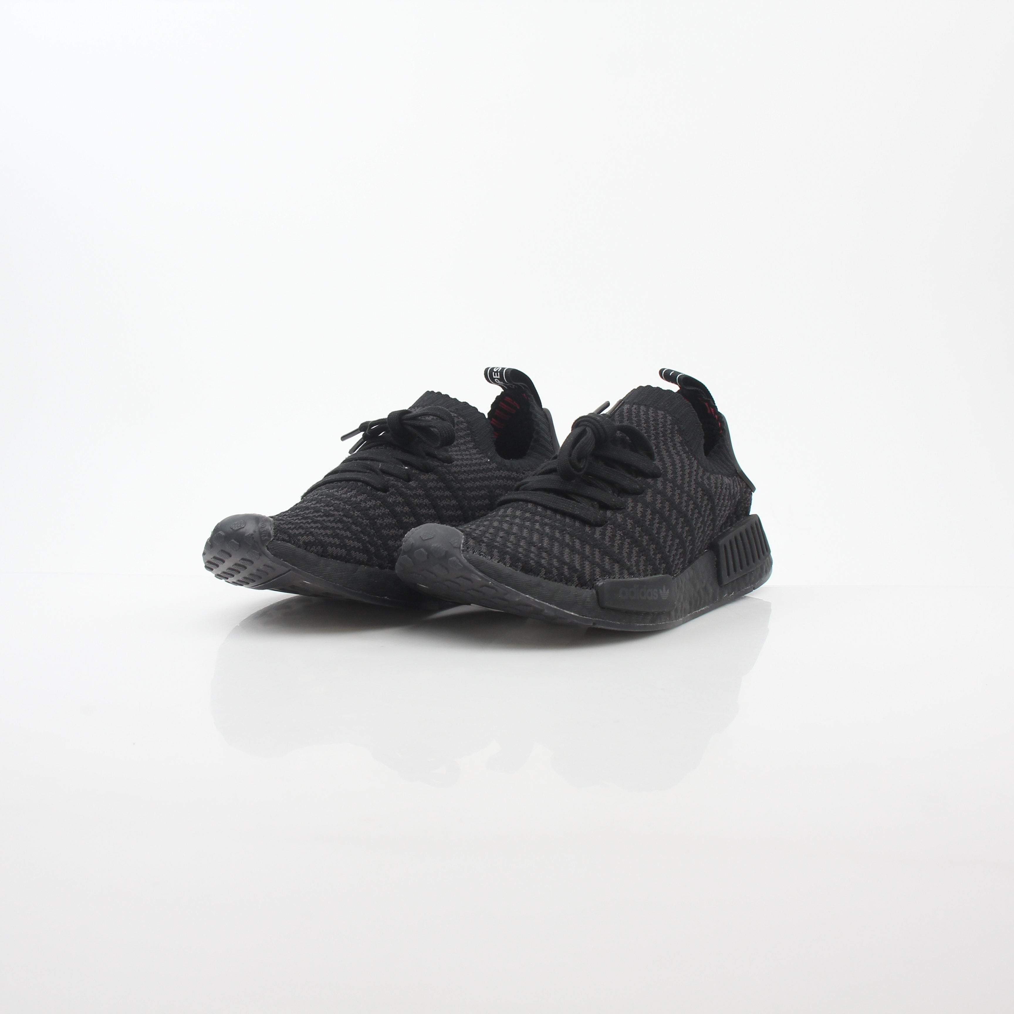 Black Adidas NMD R1 STLT Primeknit sneakers with Boost sole and white accents, displayed on a plain background.