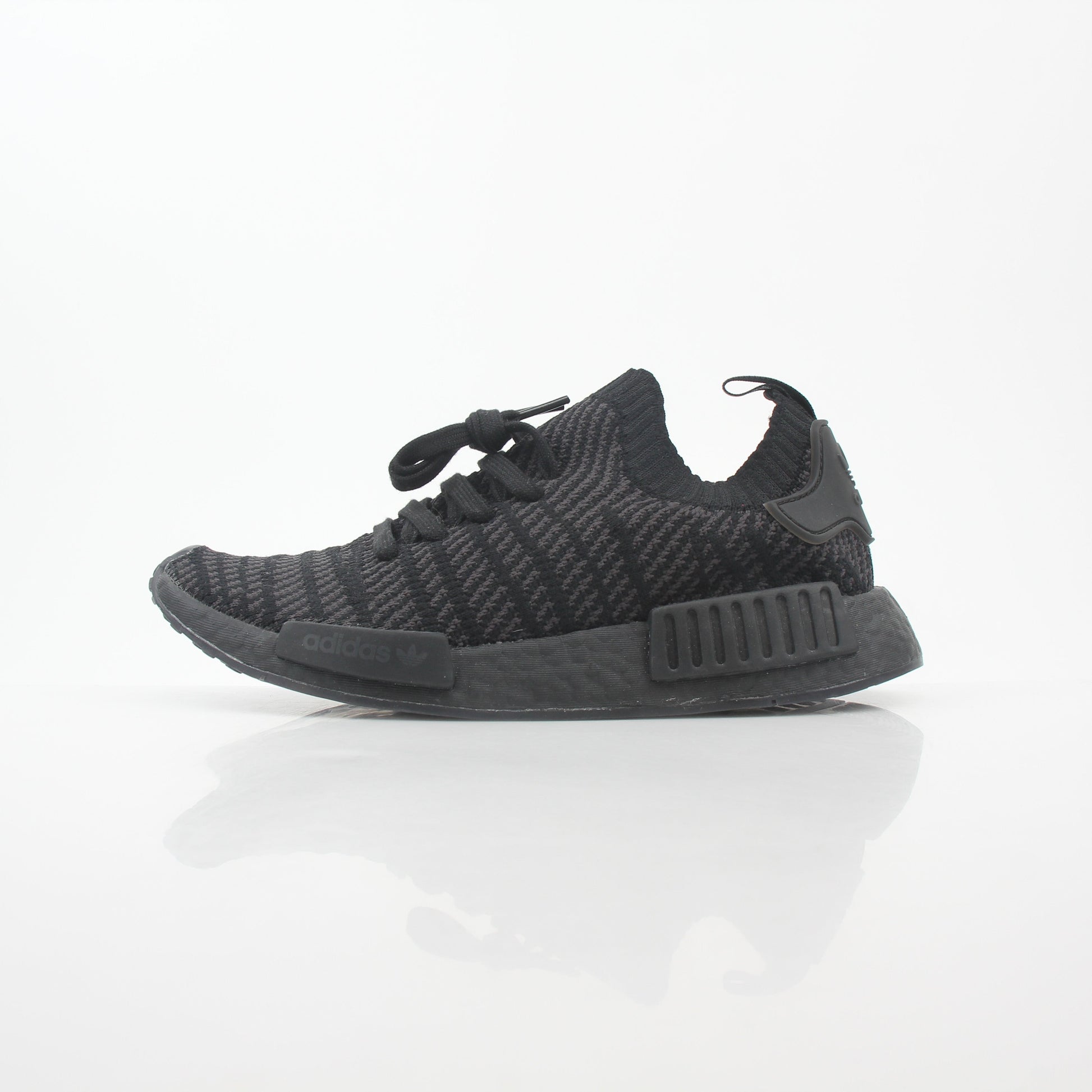 Black Adidas NMD R1 STLT Primeknit sneakers with gold accents, featuring a sleek low-profile design and Boost sole.
