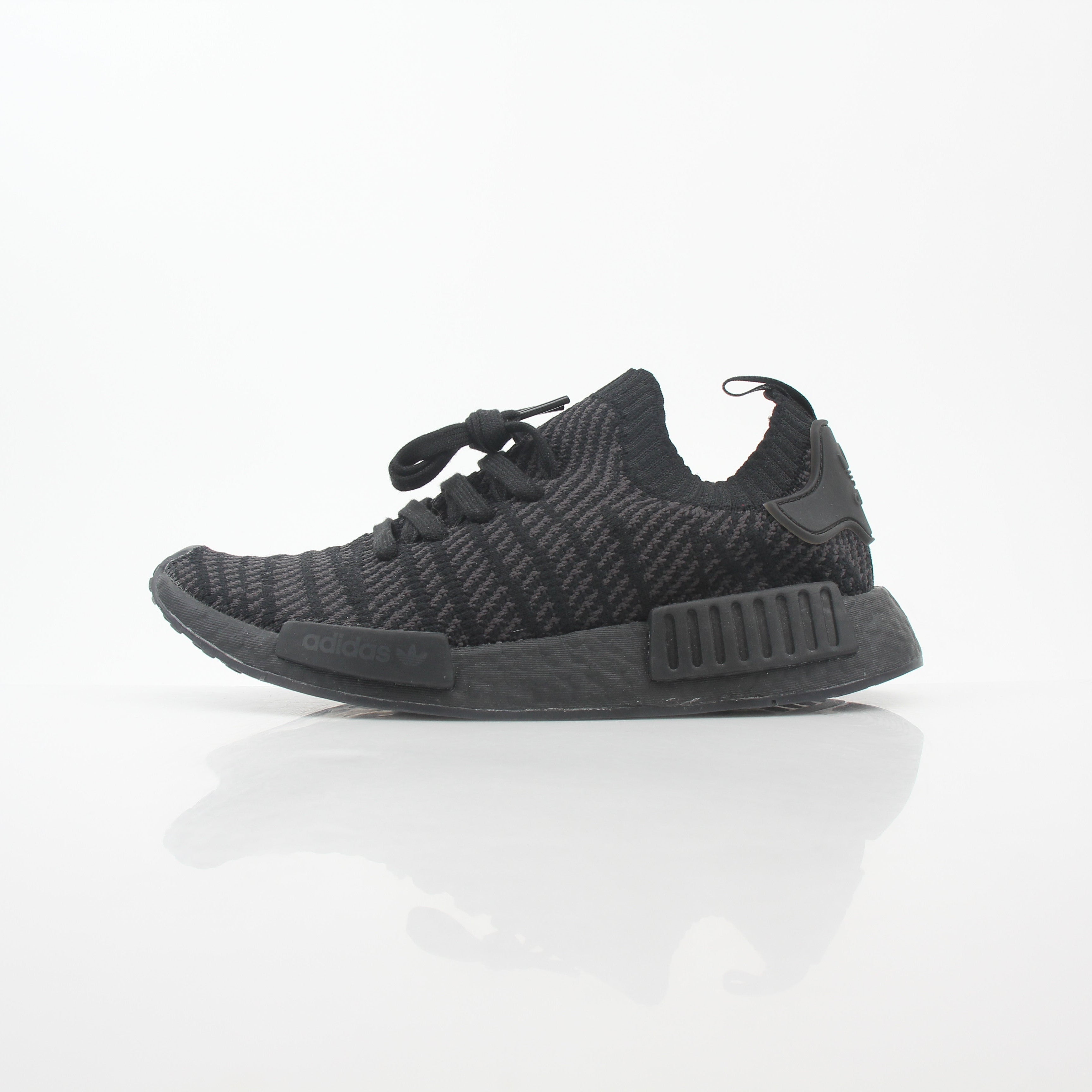 Black Adidas NMD R1 STLT Primeknit sneakers with gold accents, featuring a sleek low-profile design and Boost sole.