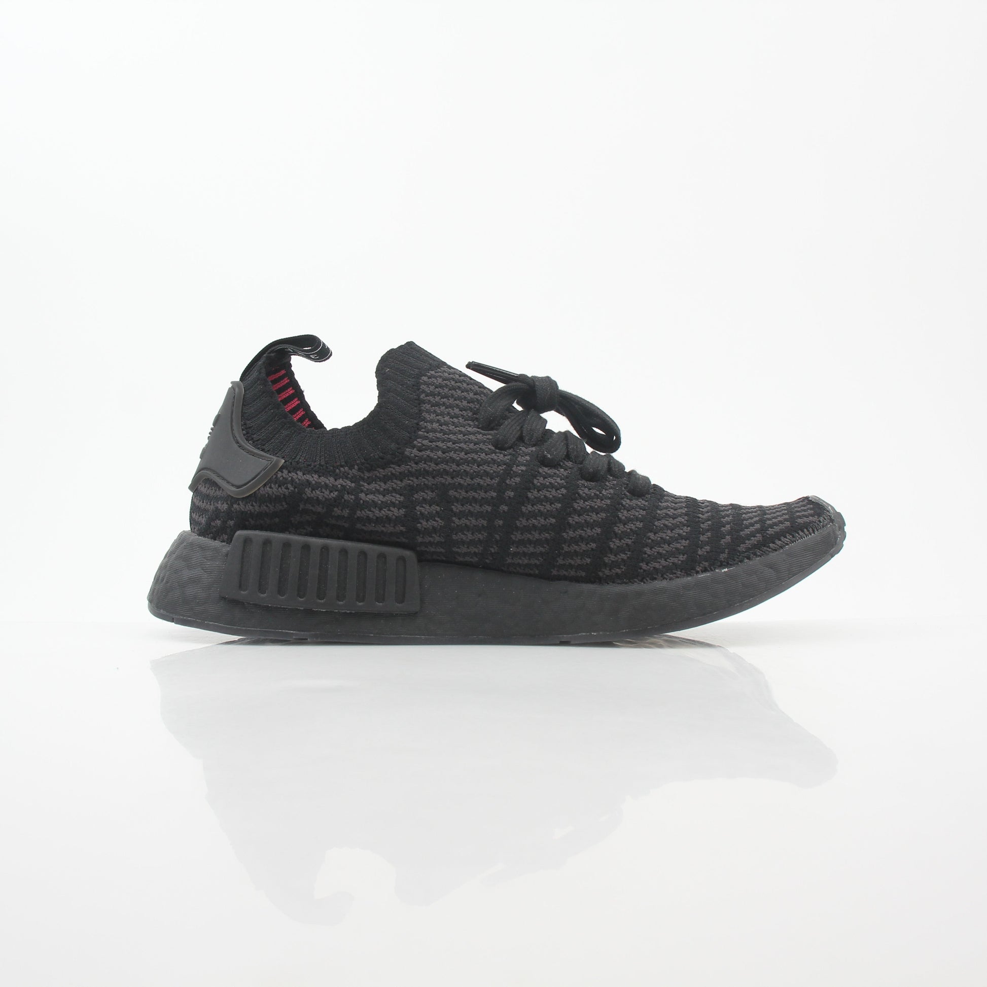 Adidas NMD R1 STLT Triple Black Primeknit sneakers with sleek black design and Boost sole, worn on a model's feet.