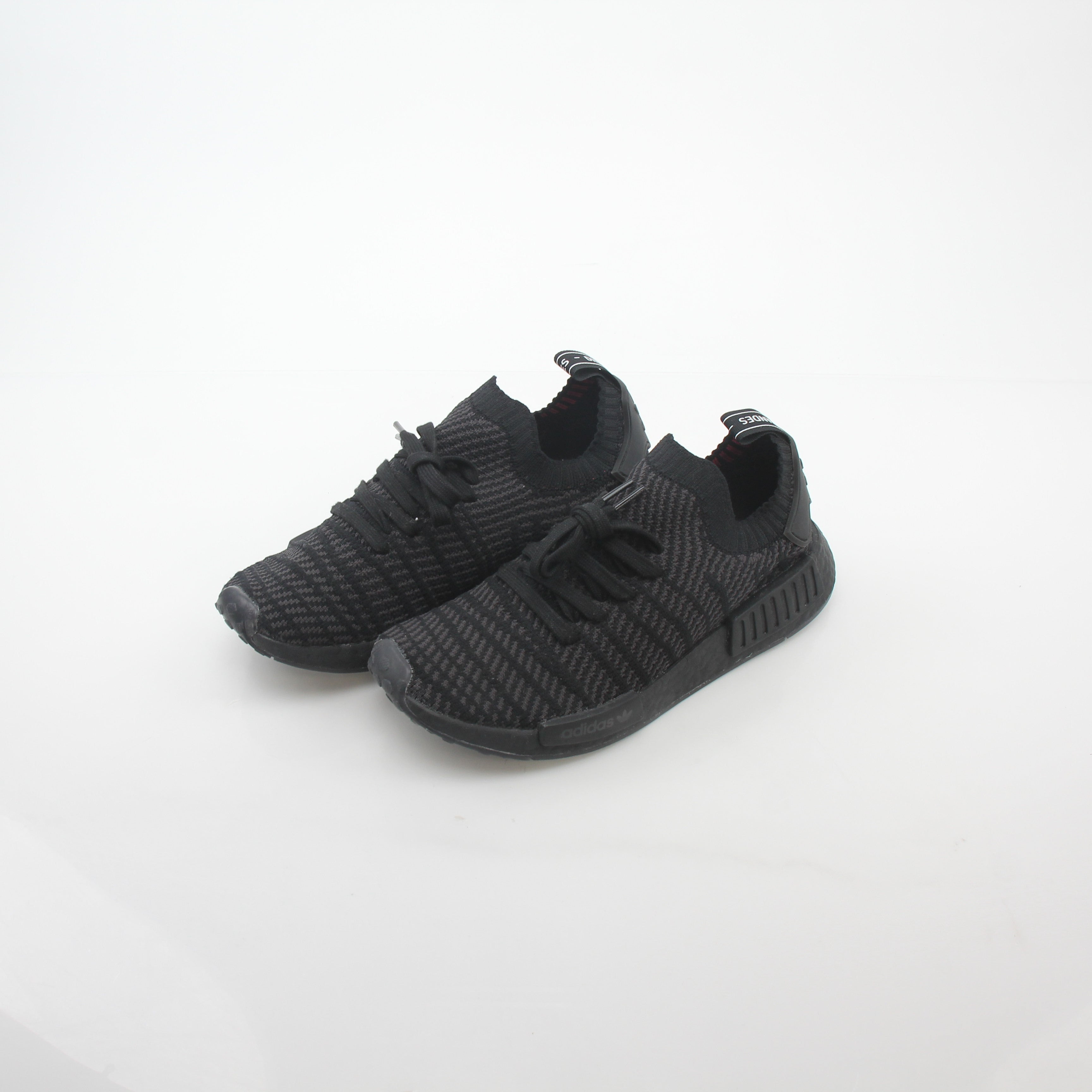 Black Adidas NMD R1 STLT Primeknit sneakers with white Boost sole, featuring sleek design and modern athletic style.