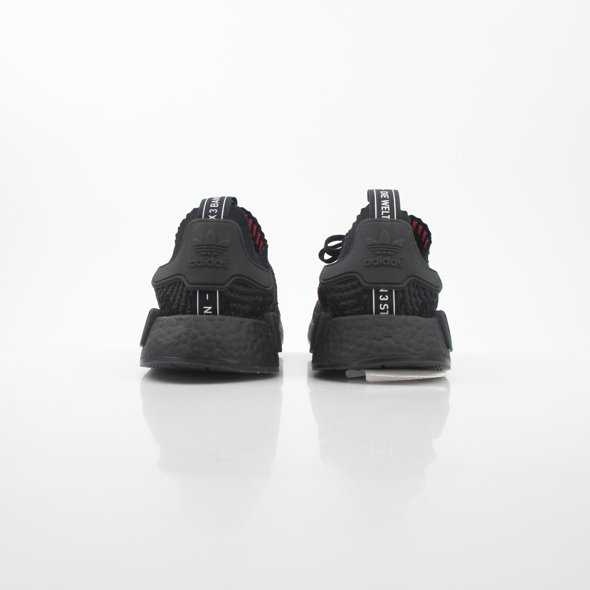 Black Adidas NMD R1 STLT Primeknit sneakers with Boost midsole and signature design, displayed on a plain background.