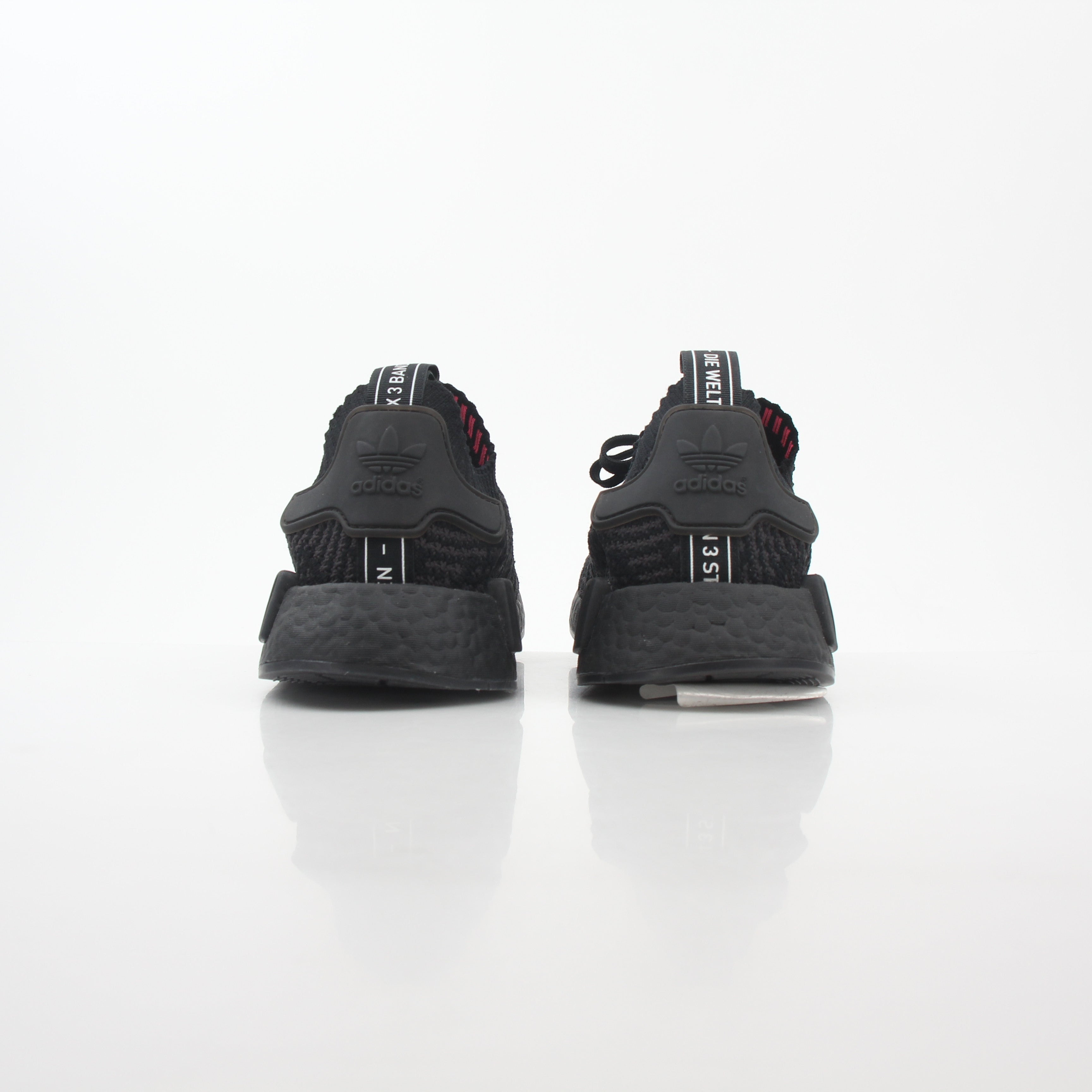 Black Adidas NMD R1 STLT Primeknit sneakers with Boost midsole and signature design, displayed on a plain background.