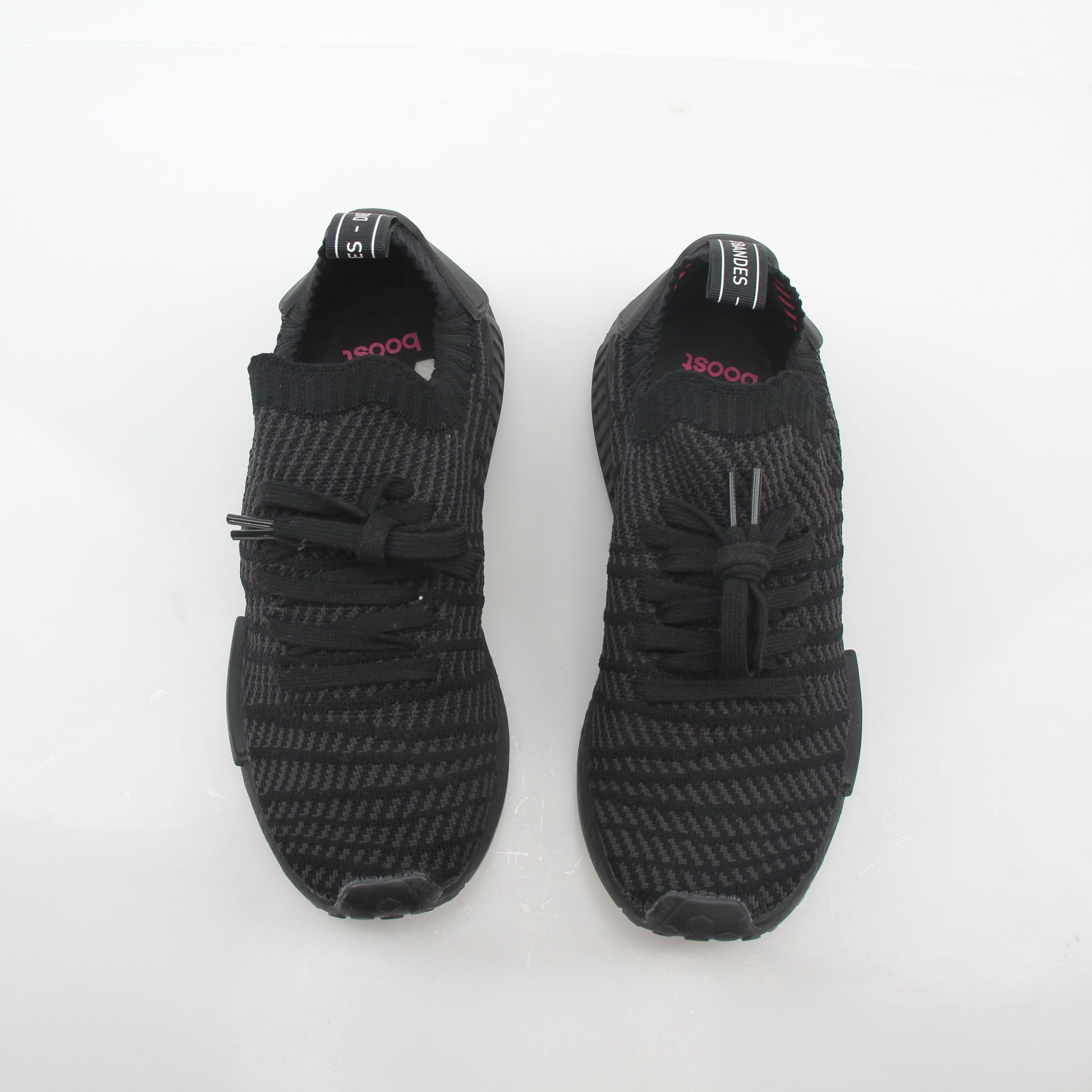 Adidas NMD R1 STLT Triple Black Primeknit sneakers in black with Boost midsole and signature branding on the side.